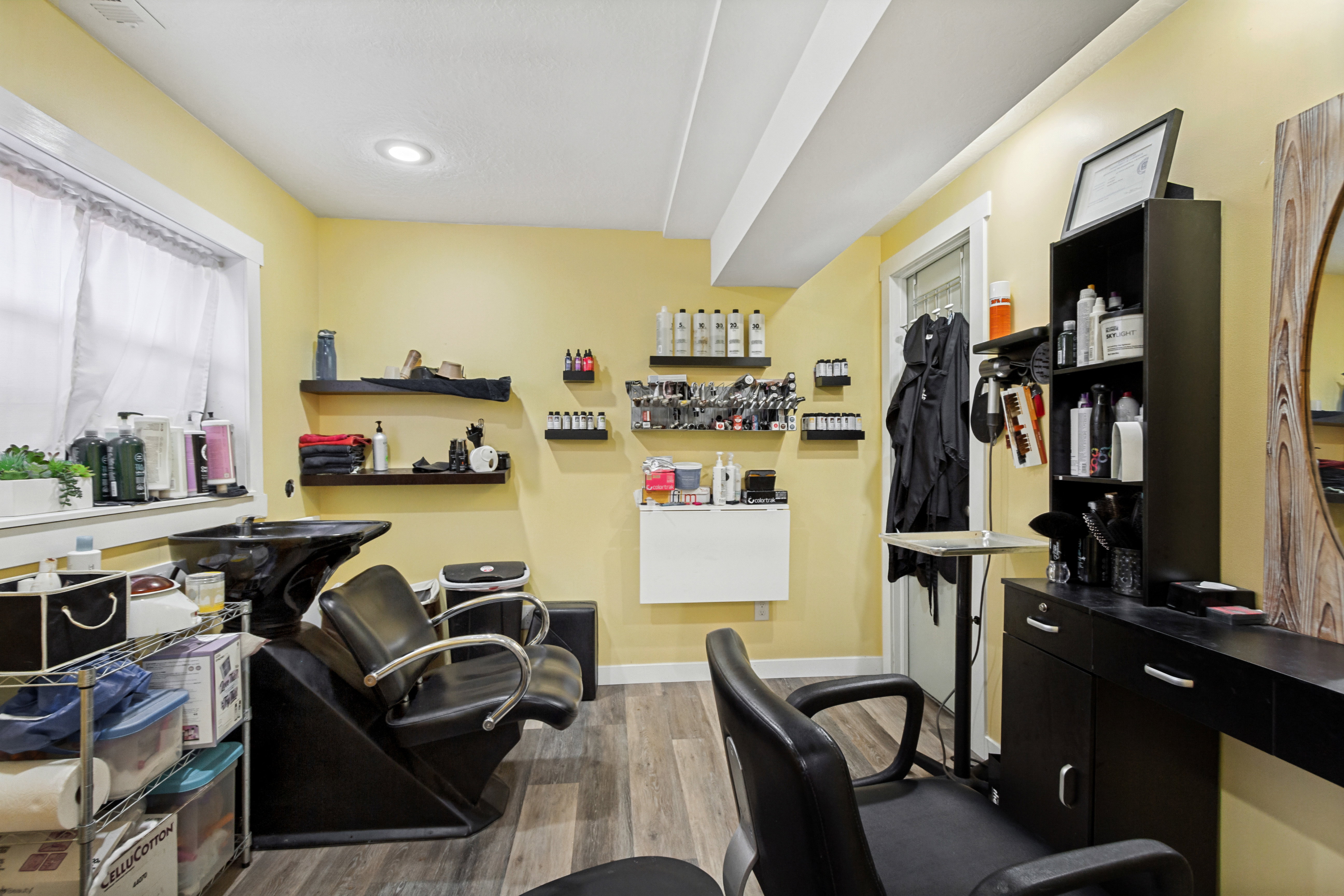 Dedicated salon space featuring light yellow walls and wood-finish flooring