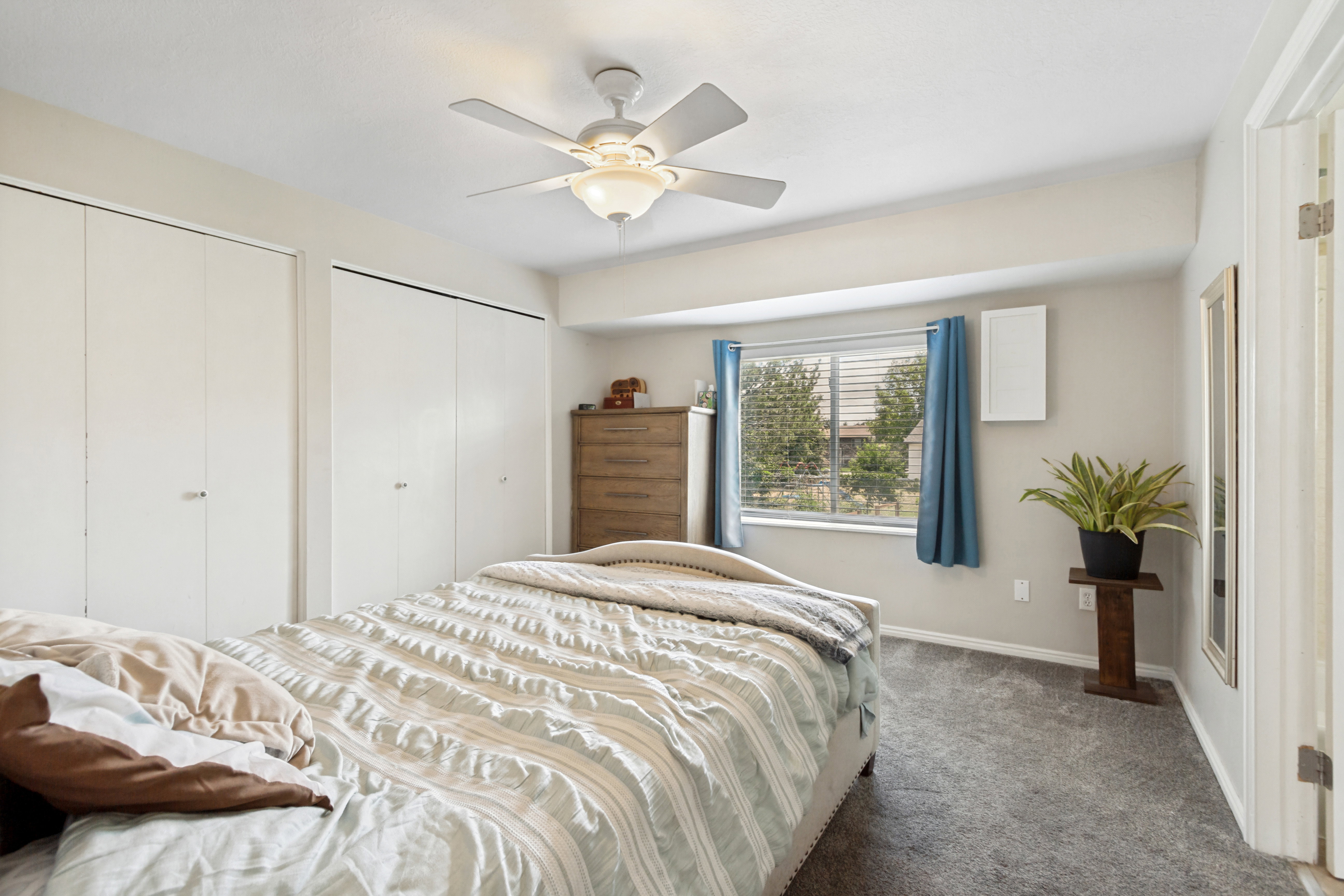 Bedroom featuring a window with blinds, two closet doors, a ceiling fan with integrated lighting, and carpet flooring