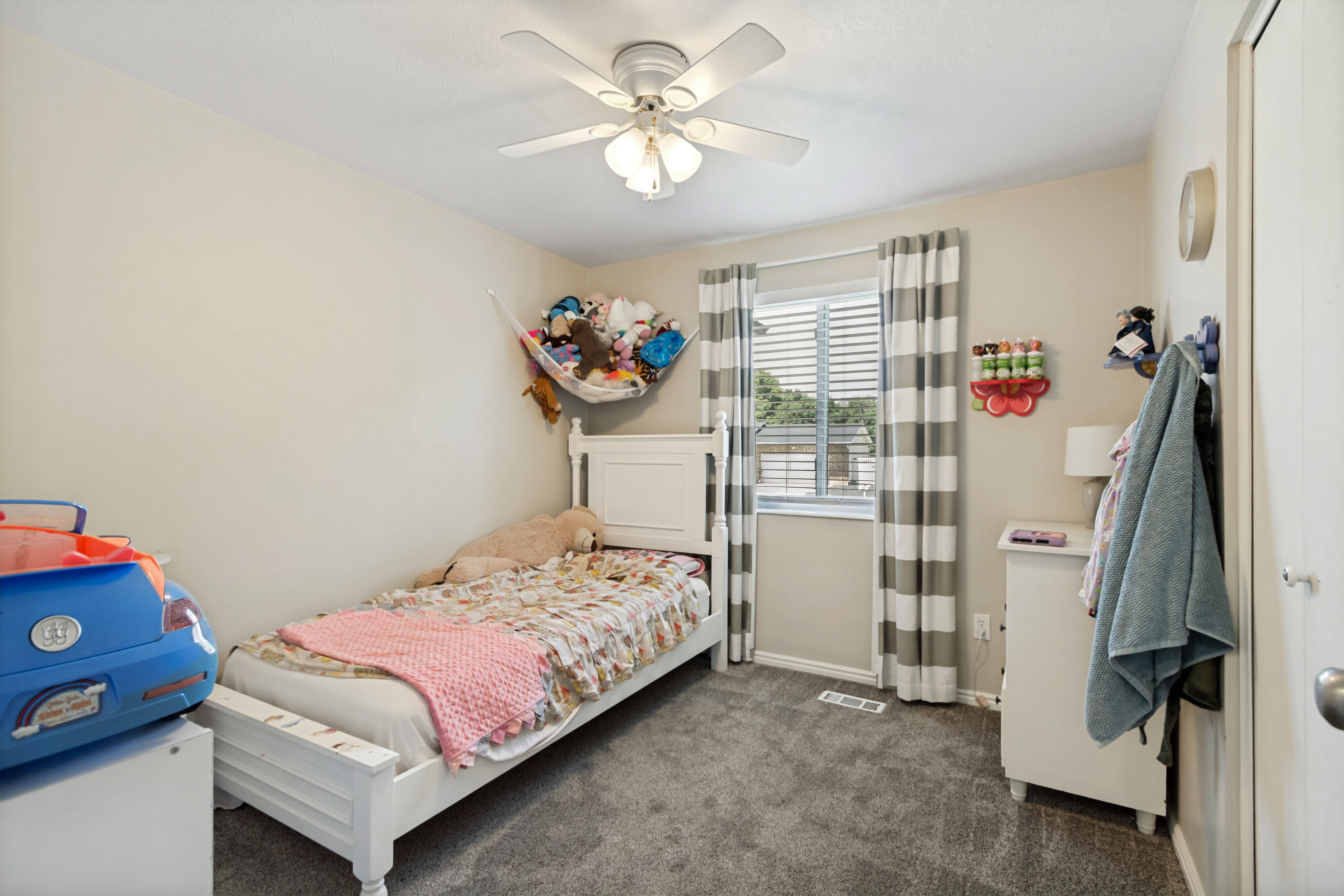 Bedroom featuring neutral wall paint, gray carpet flooring, a ceiling fan with integrated lighting, and a window with blinds