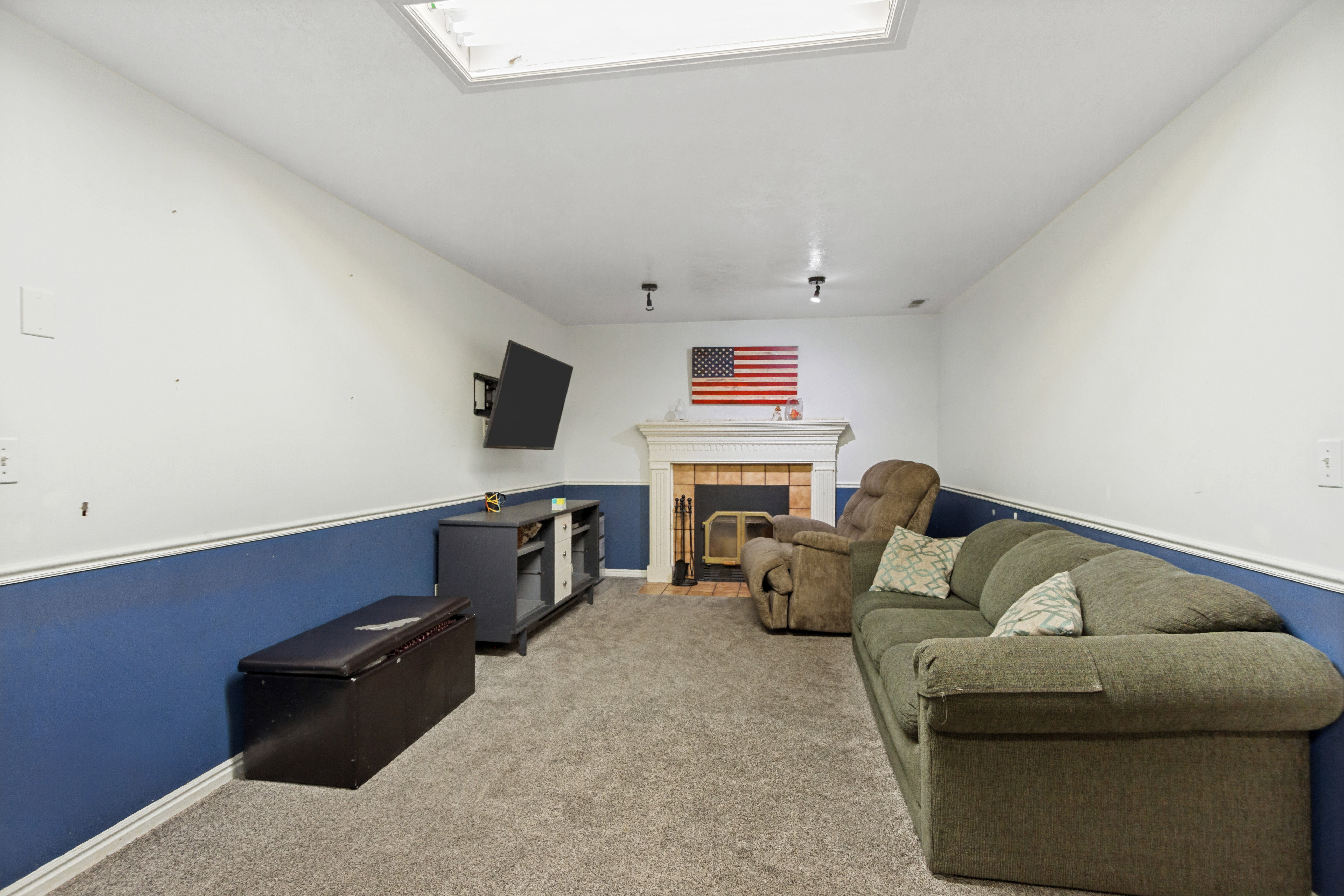 Carpeted room featuring a fireplace with a white mantel and a brick surround, a built-in ceiling light fixture, and track lighting
