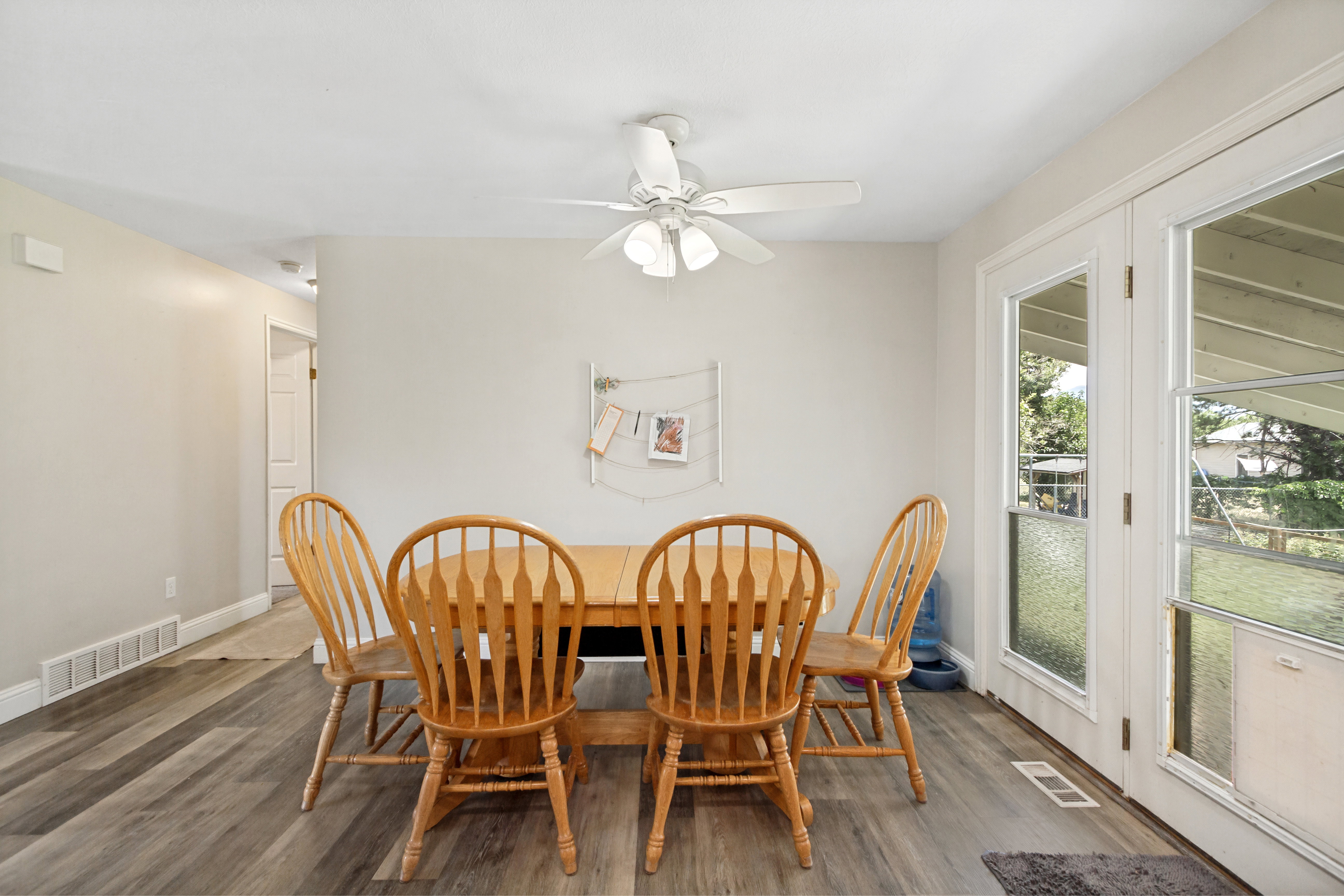 Dining area featuring wood-finish flooring, light-toned walls, and a ceiling fan with integrated lighting