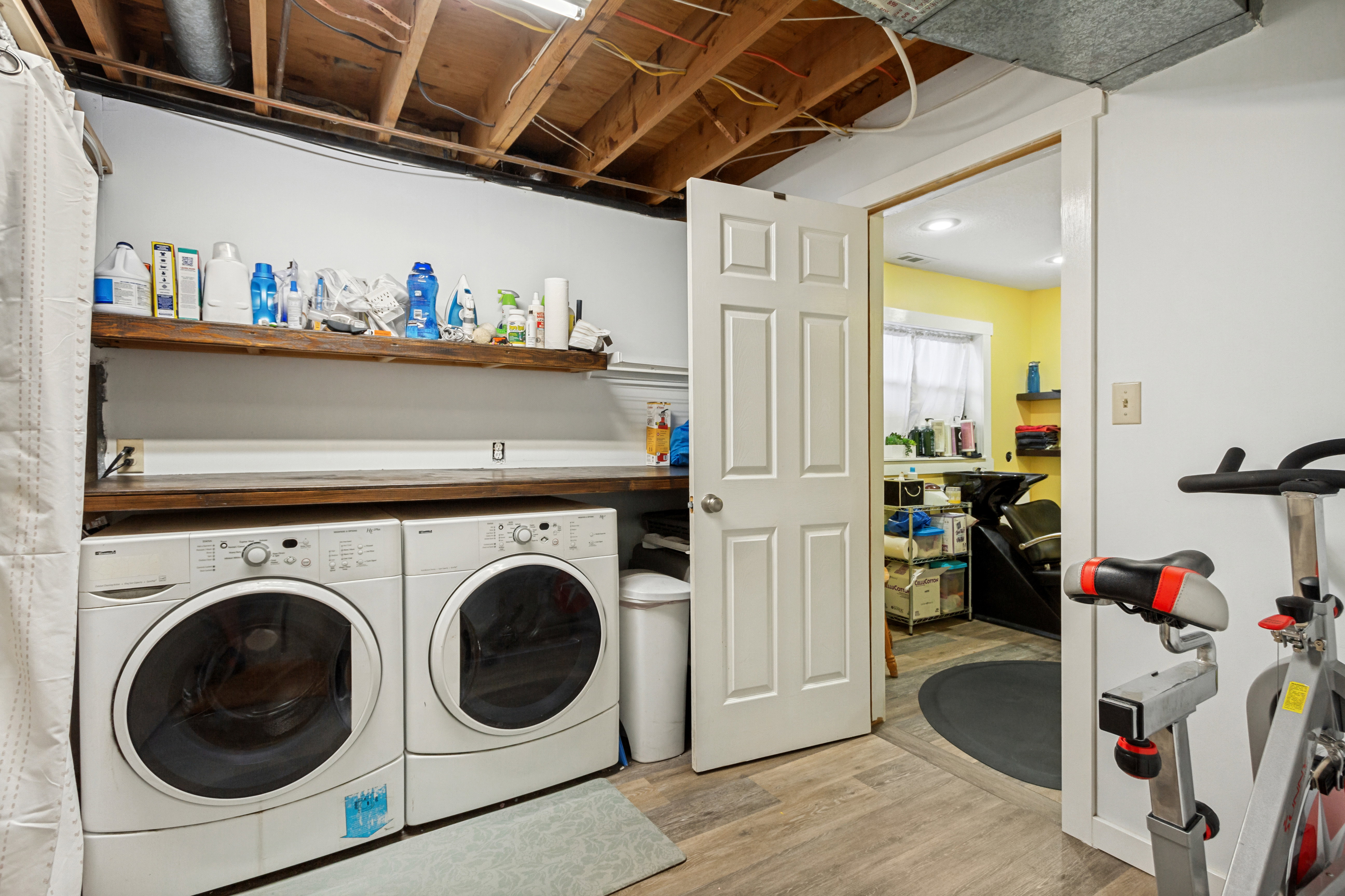 Functional laundry area featuring wood-finish flooring and an exposed beam ceiling