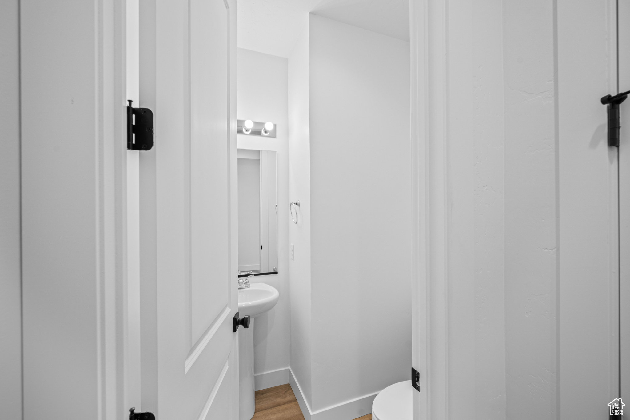 Compact powder room featuring a pedestal sink, wall-mounted mirror, and overhead vanity lighting. This is not the actual home being built but a representation of the features available in this home. Colors and finishes may differ from those shown.