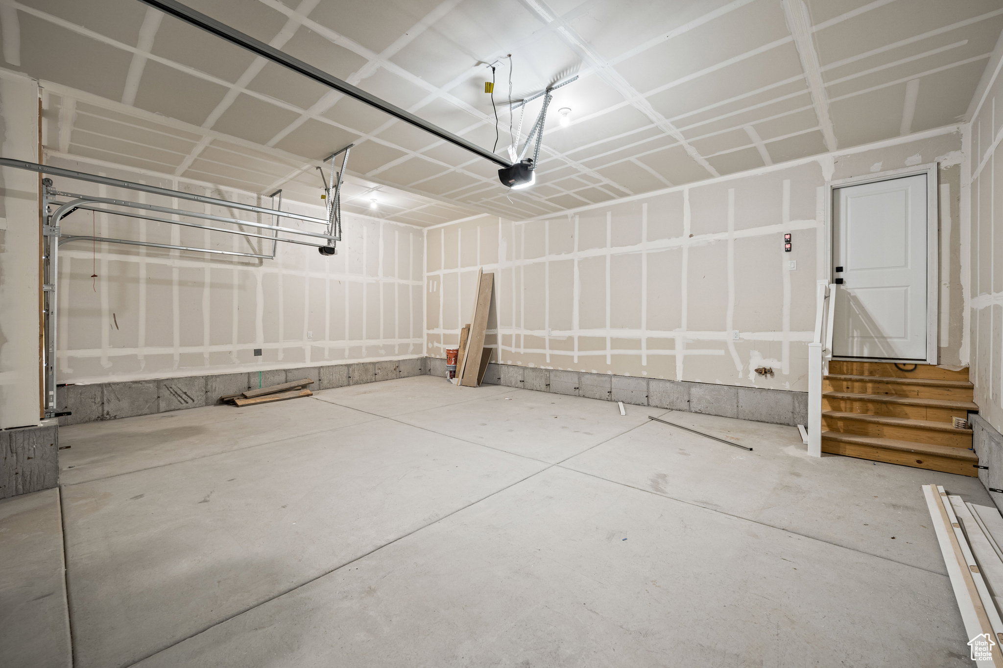 Spacious garage with unfinished drywall, concrete flooring, and an overhead garage door mechanism. This is not the actual home being built but a representation of the features available in this home. Colors and finishes may differ from those shown.