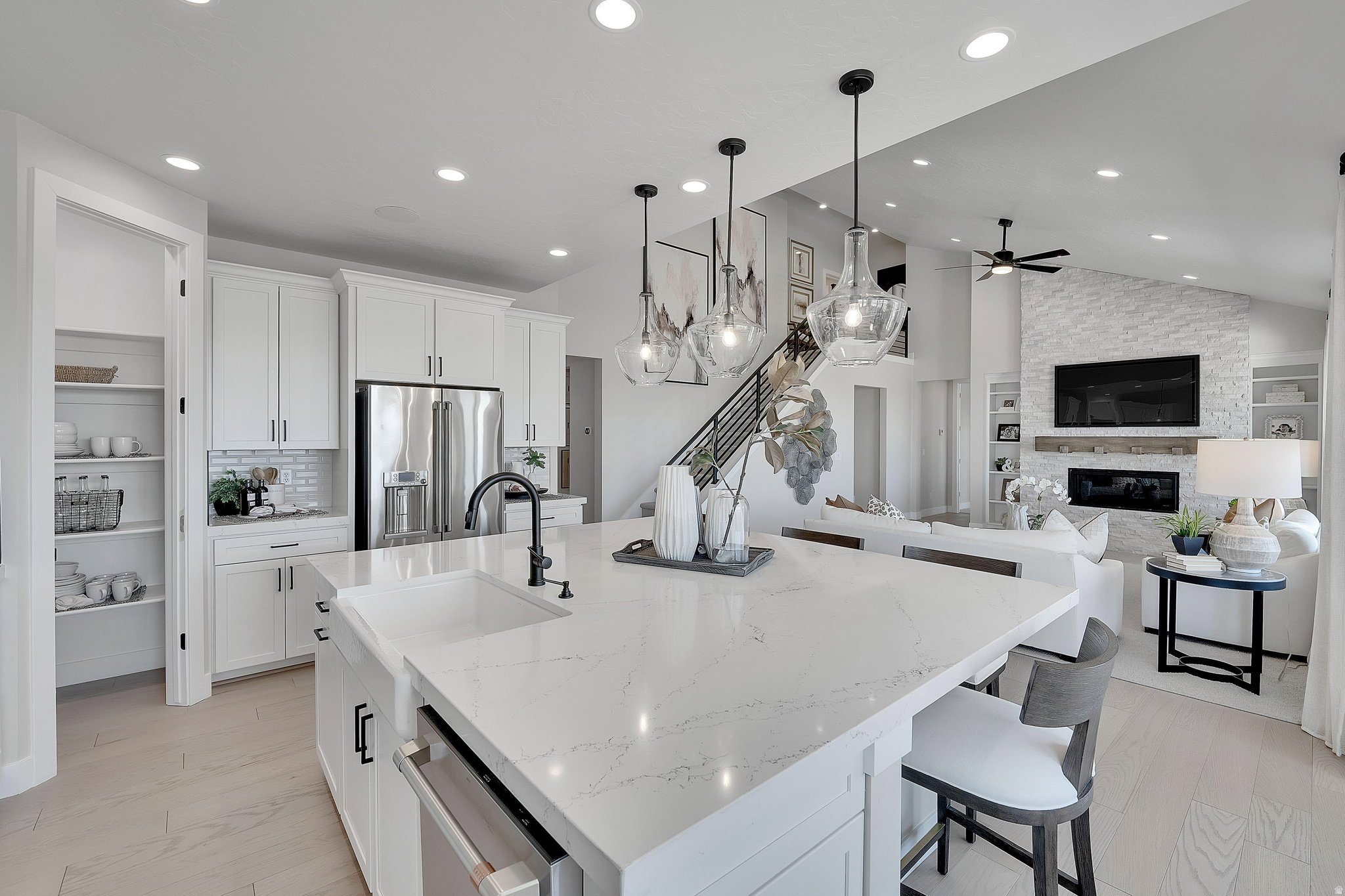 Open-concept living space featuring a spacious kitchen island with a built-in sink, white cabinetry, stainless steel appliances, and wood-finish flooring. This is not the actual home being built but a representation of the features available in this home.