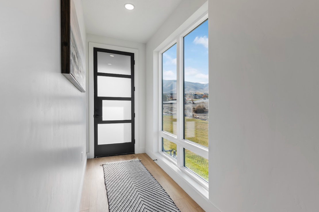 Entryway featuring a contemporary black door with frosted glass panels, wood-finish flooring, recessed lighting, and a large multi-pane window