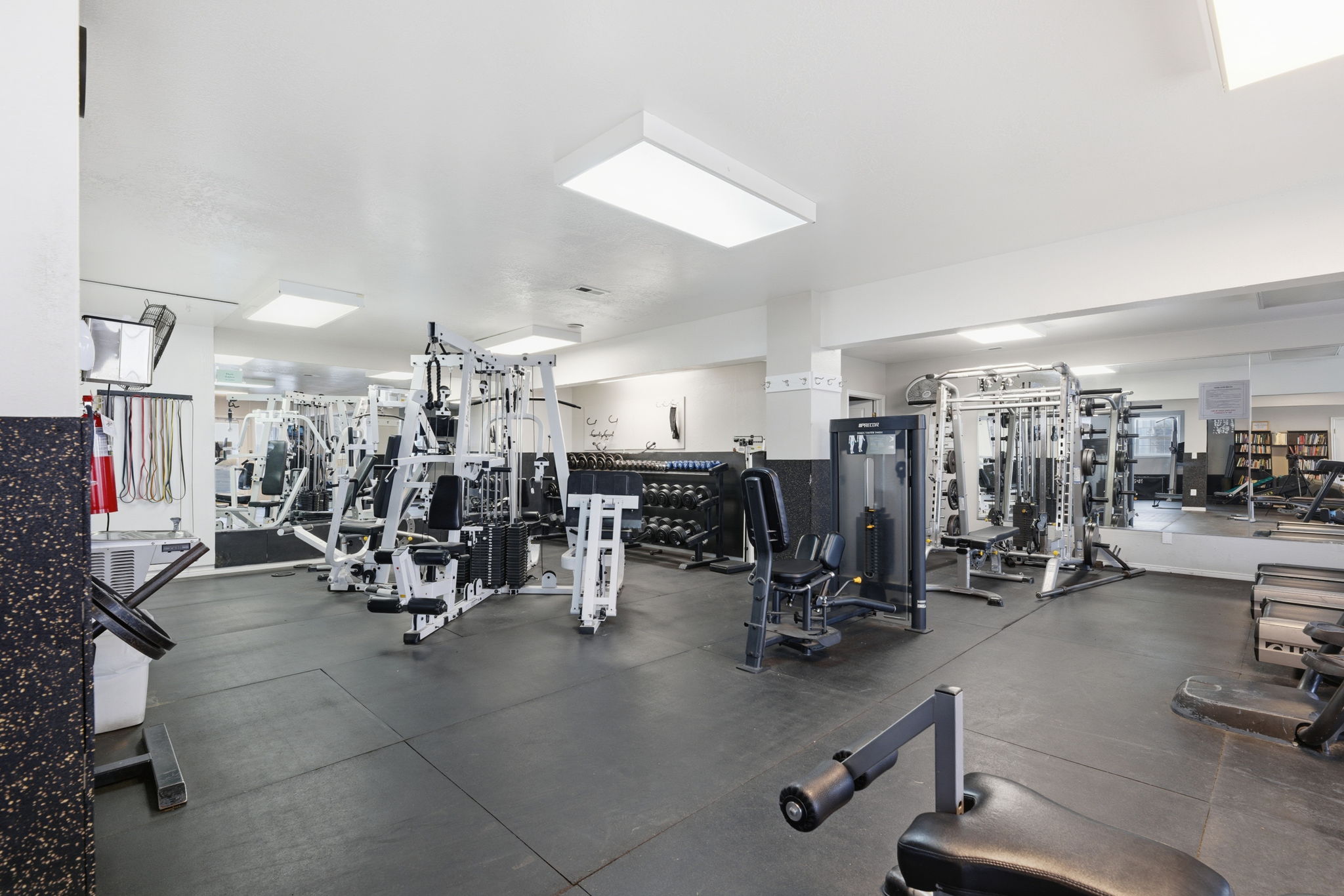 Fitness room featuring rubberized flooring, mirrored wall, and overhead lighting