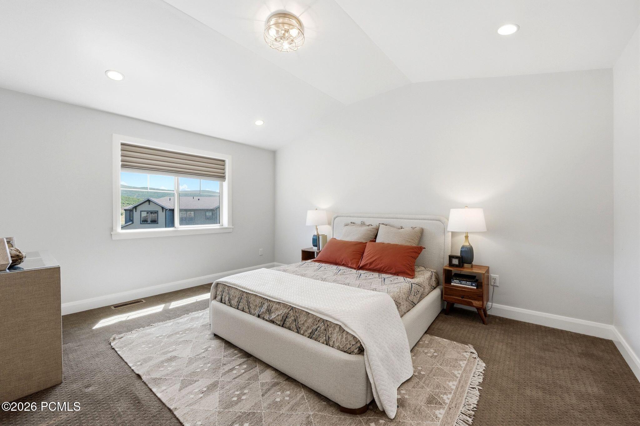 Bedroom featuring a vaulted ceiling with recessed lighting and a central chandelier