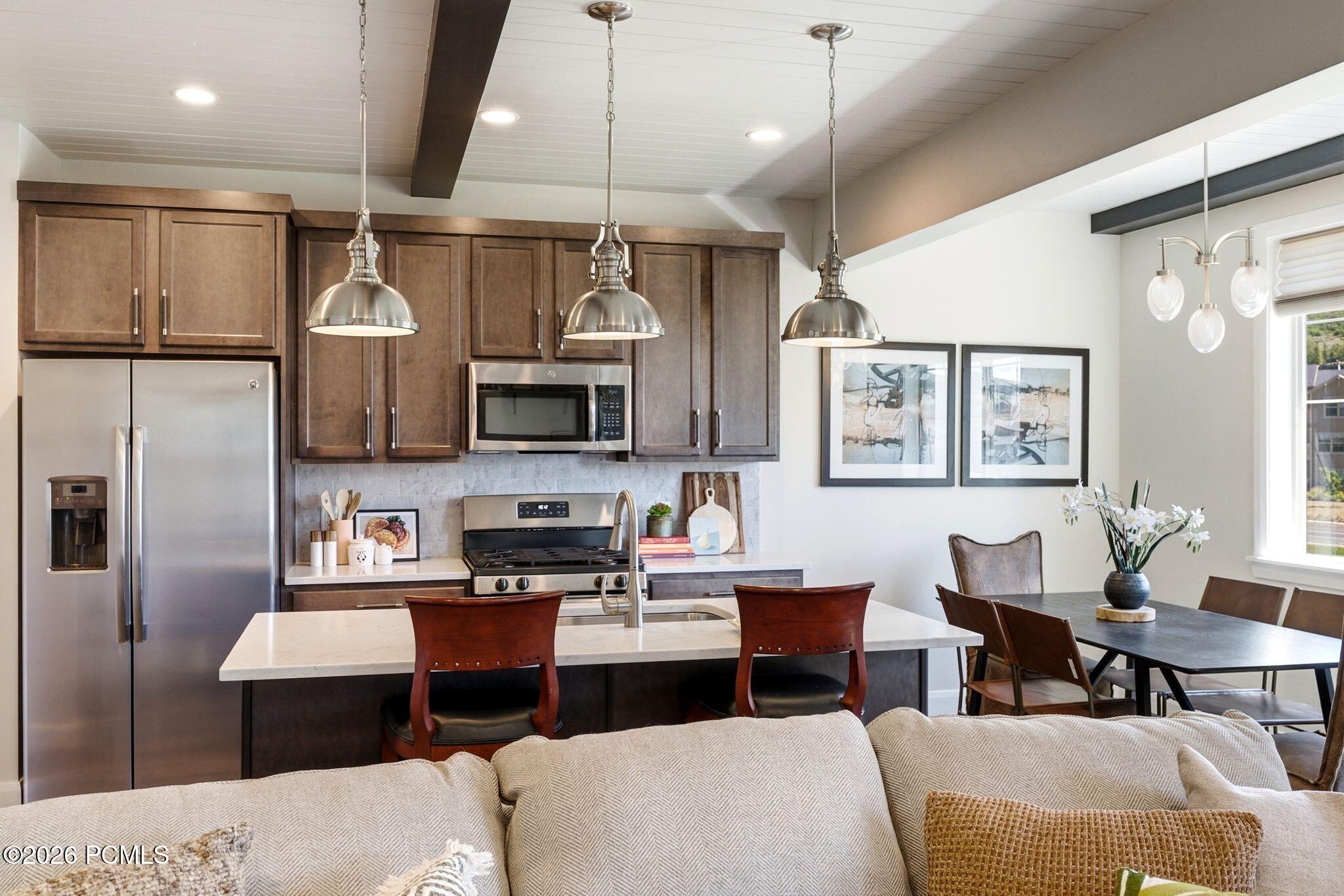 Open-concept kitchen featuring stainless steel appliances, white countertops, and dark wood-finish cabinetry