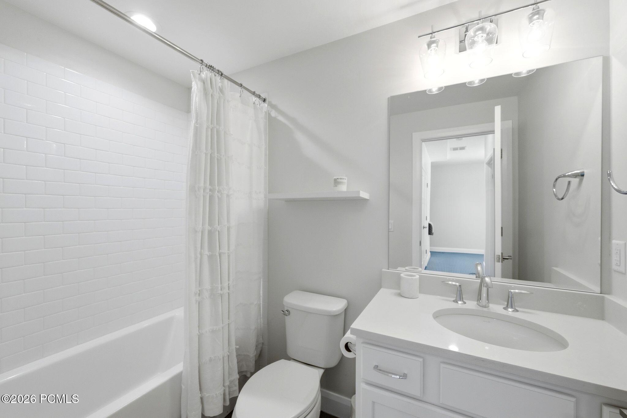 Full bathroom featuring a white subway tile surround, white bathtub, white vanity with an undermount sink, and a large wall-mounted mirror
