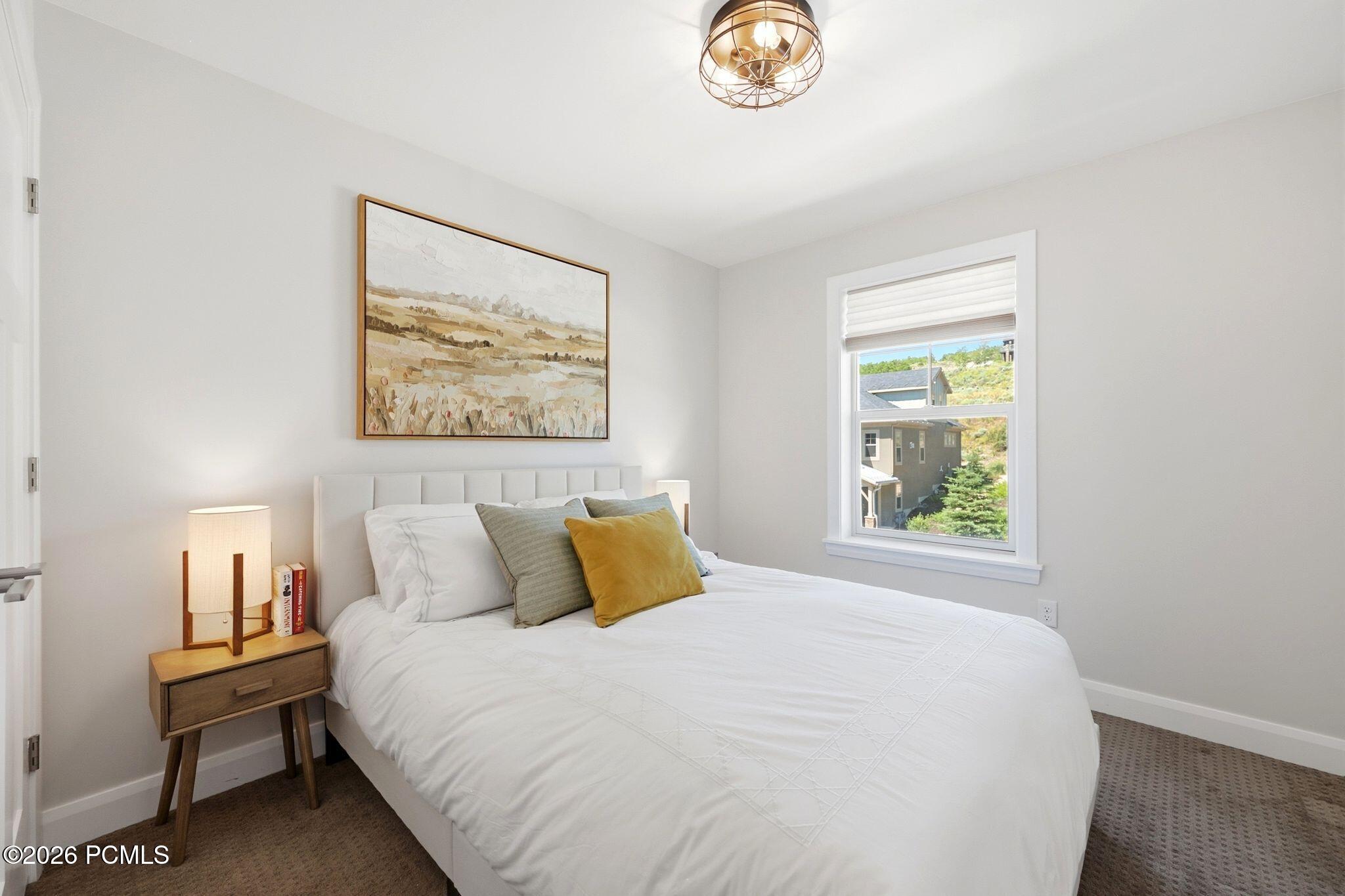 Bedroom featuring light gray walls, plush carpet flooring, a single window with white trim, and a contemporary ceiling fixture