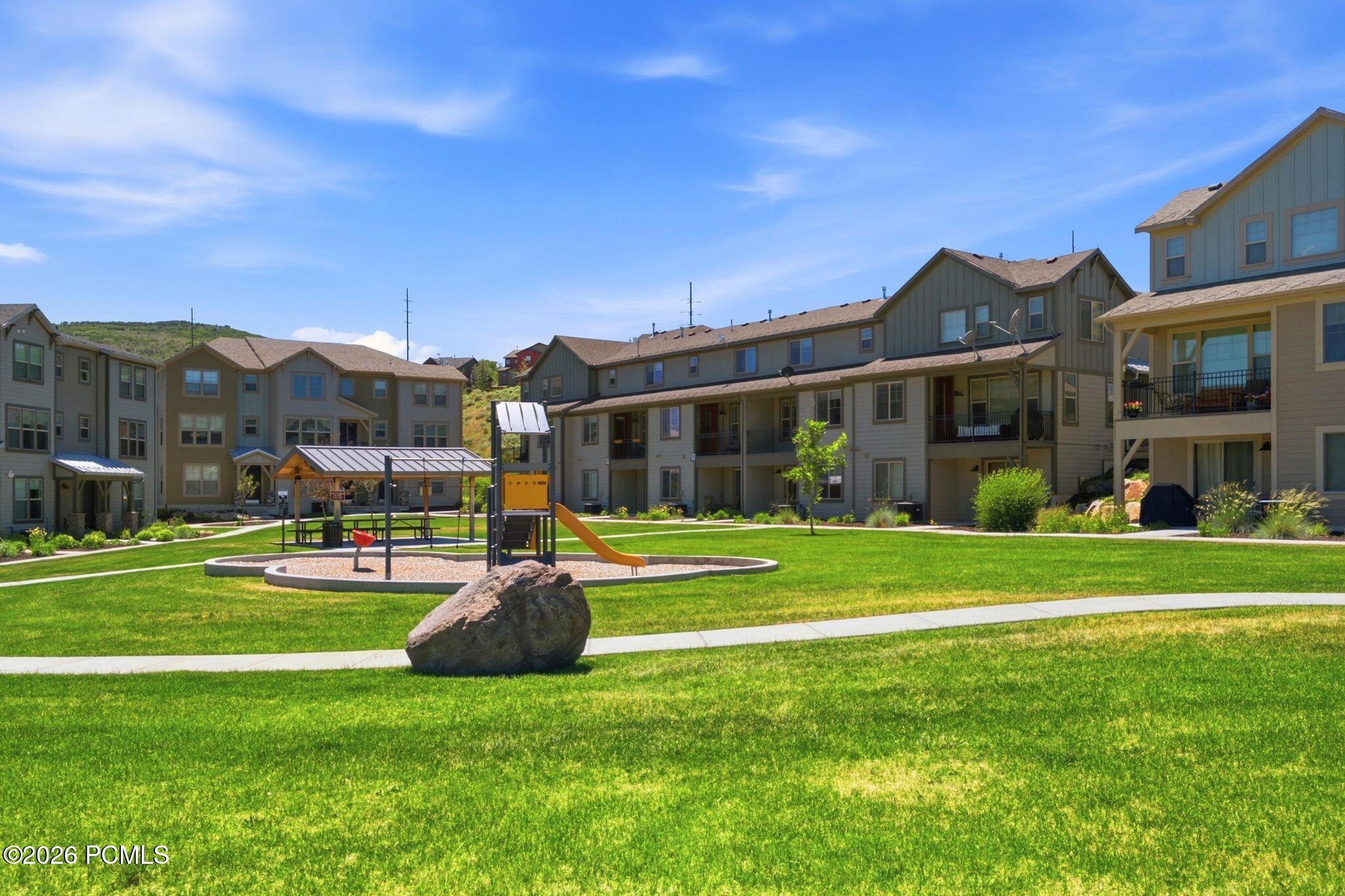 Expansive green space featuring a playground with a slide and covered picnic area
