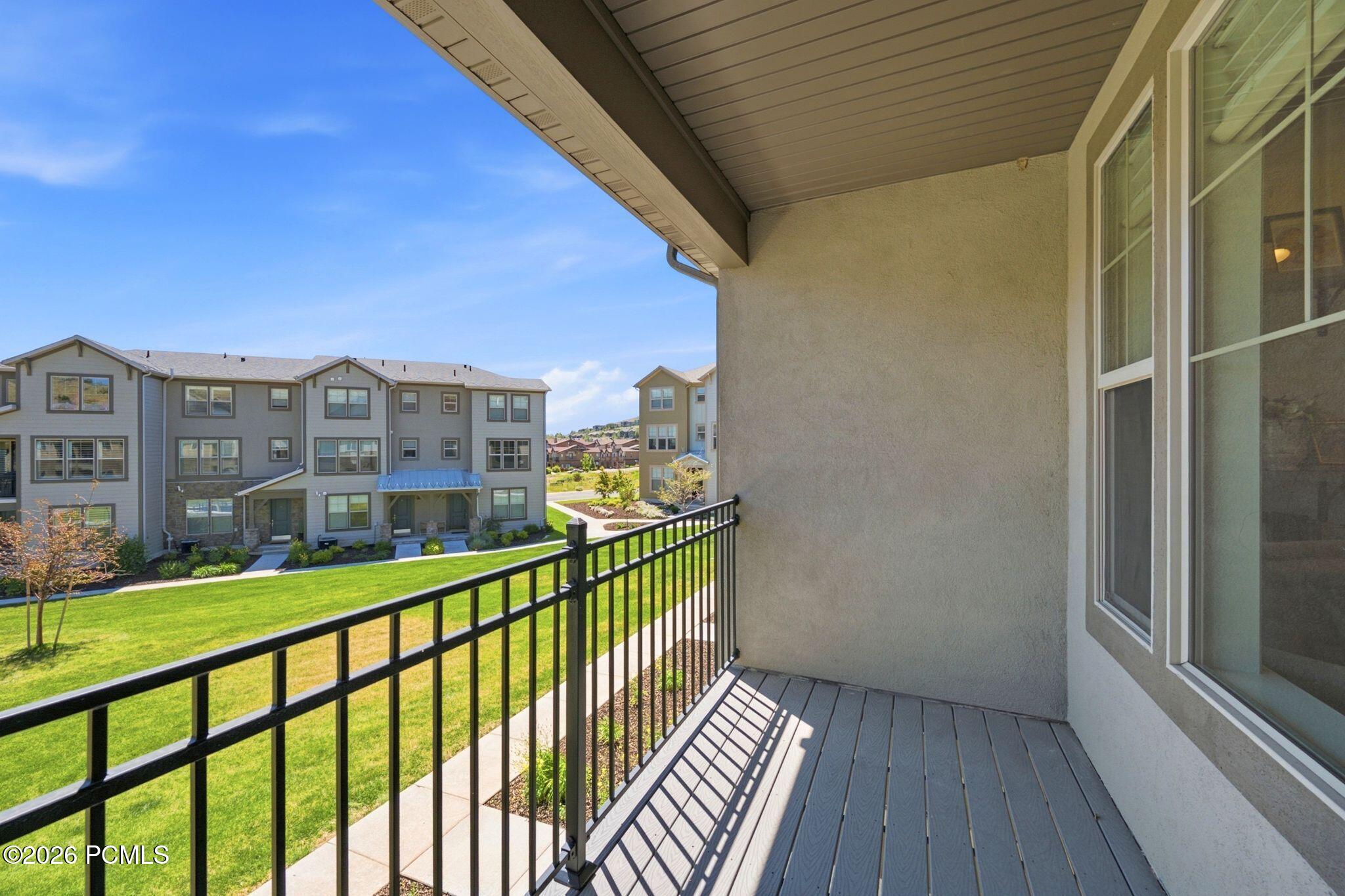 Private balcony with wood-finish flooring and black metal railing