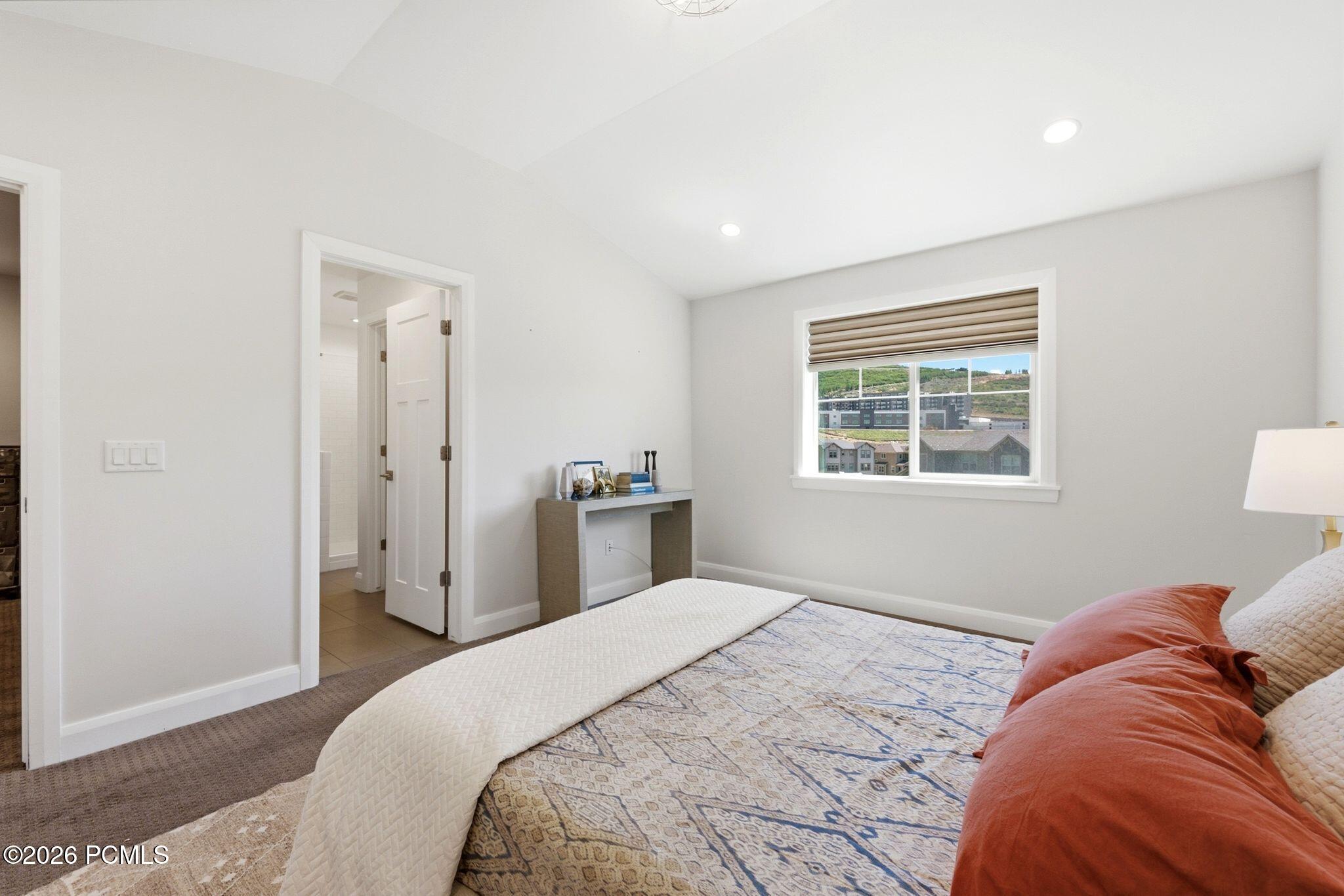 Carpeted room with recessed lighting and a window featuring a Roman shade