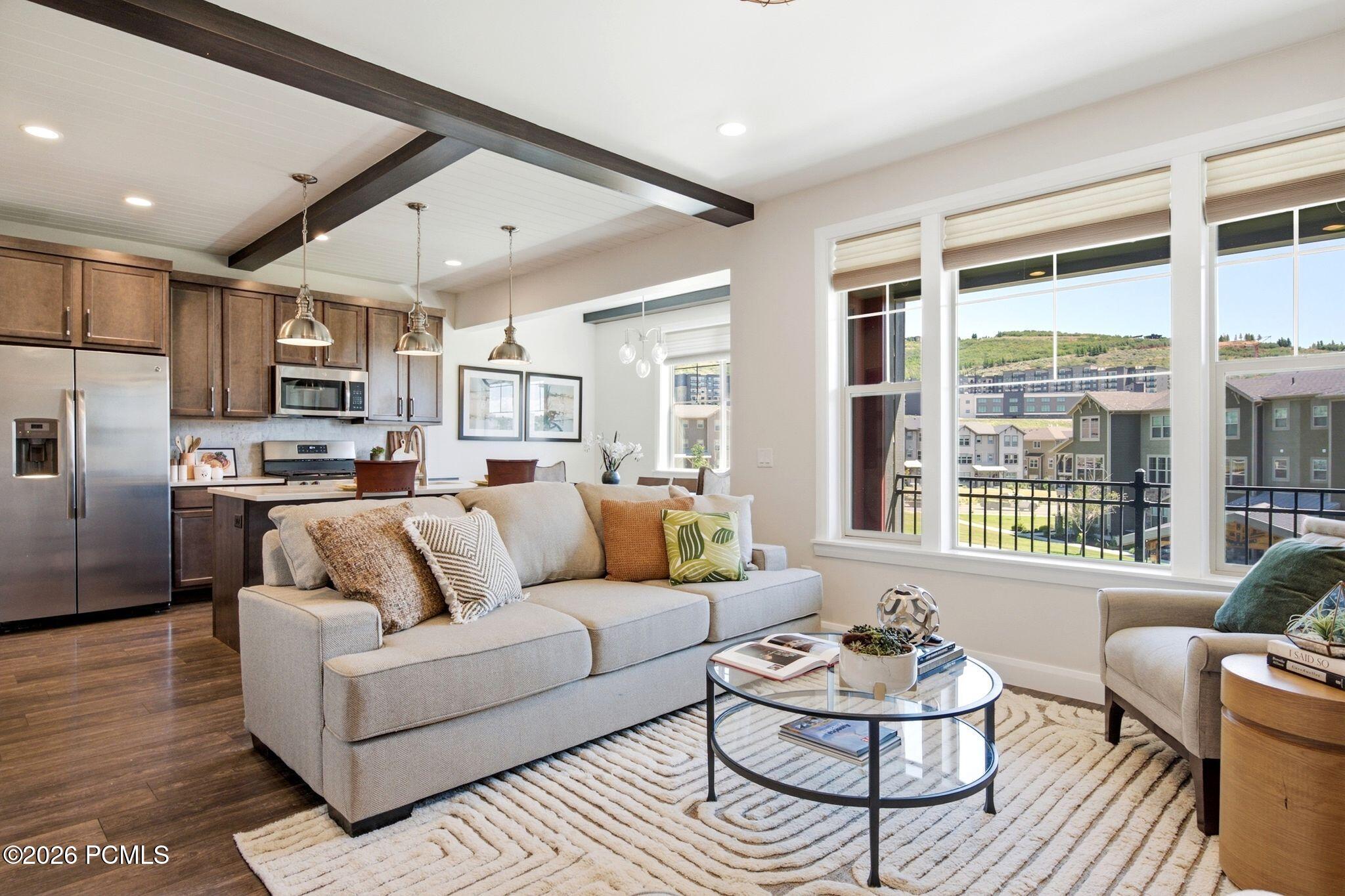 Open-concept living space featuring wood-finish flooring and beamed ceilings