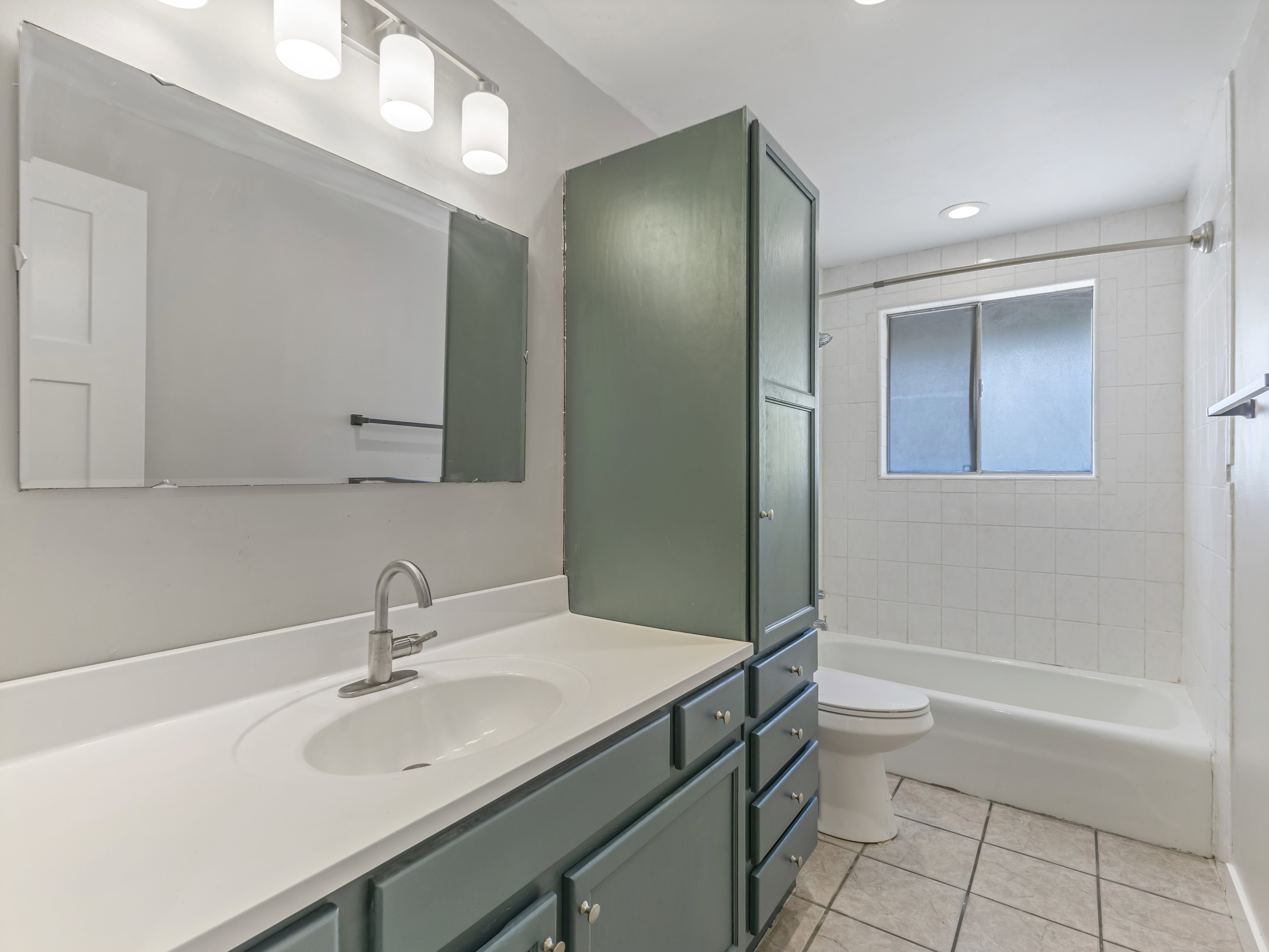 Bathroom featuring a single-sink vanity with white countertop, chrome faucet, and teal cabinetry