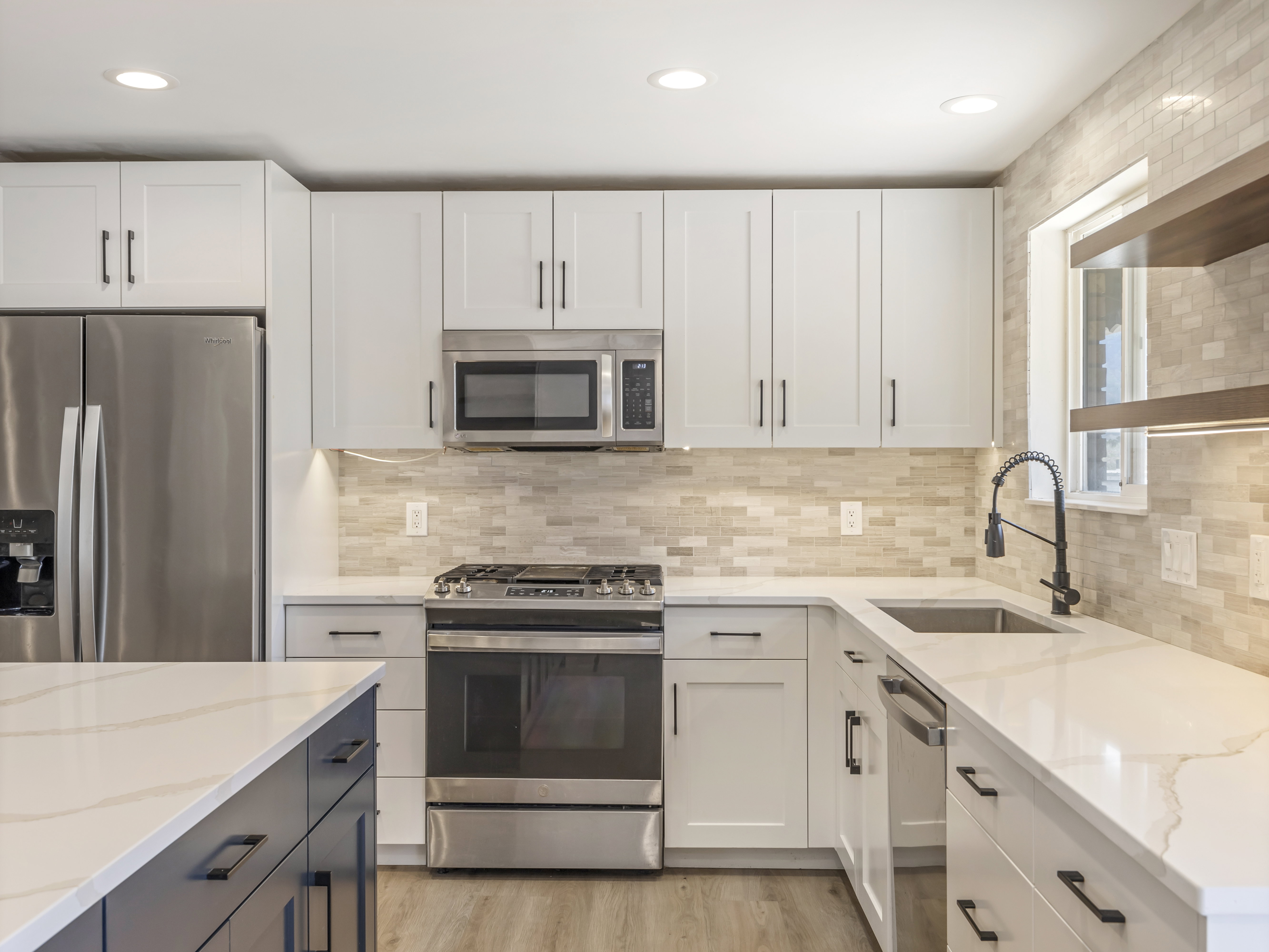 Contemporary kitchen with white shaker cabinetry, stainless steel appliances, and a light-toned tile backsplash