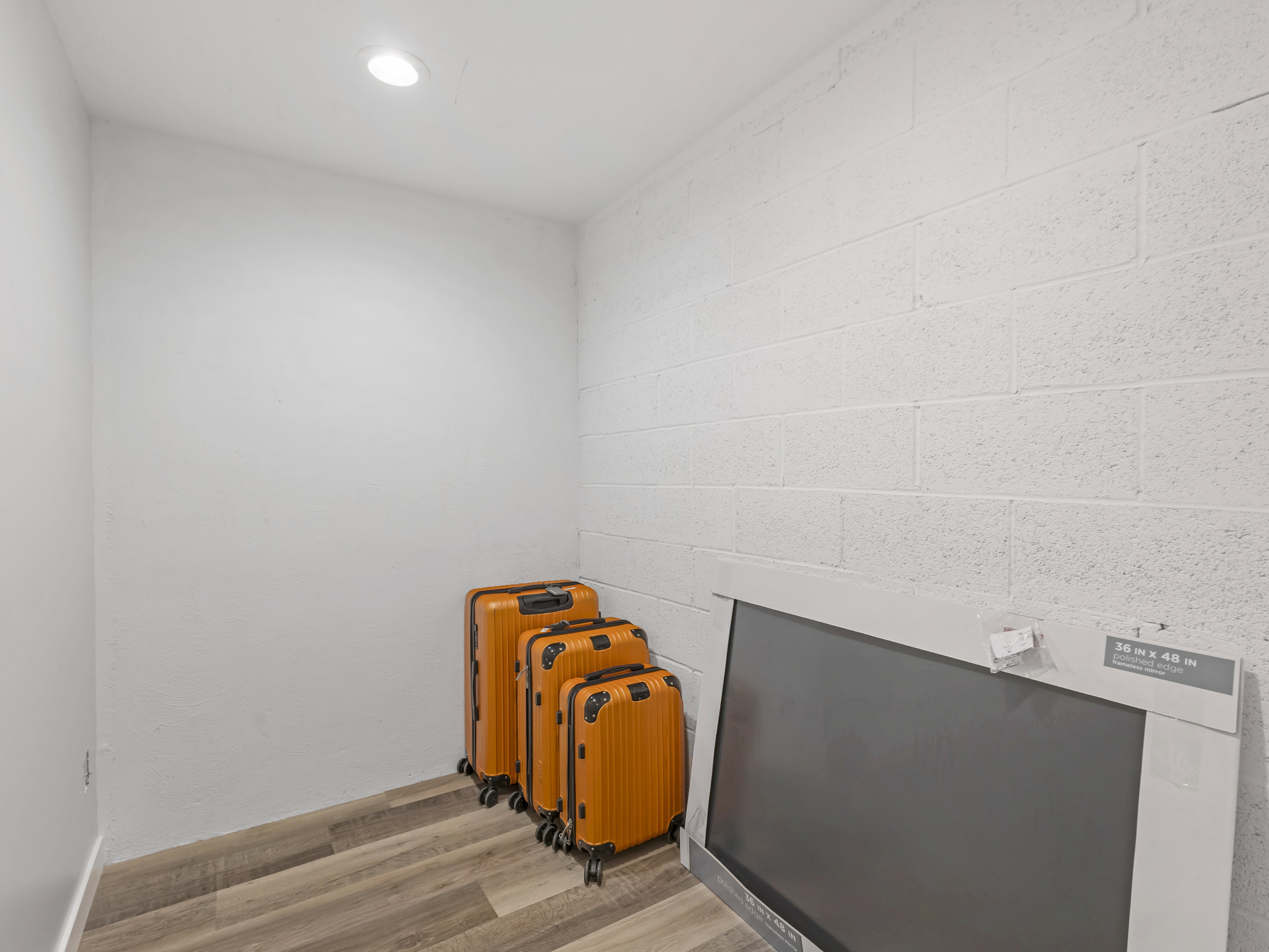 Compact storage area featuring wood-finish flooring, white painted walls, and a recessed ceiling light