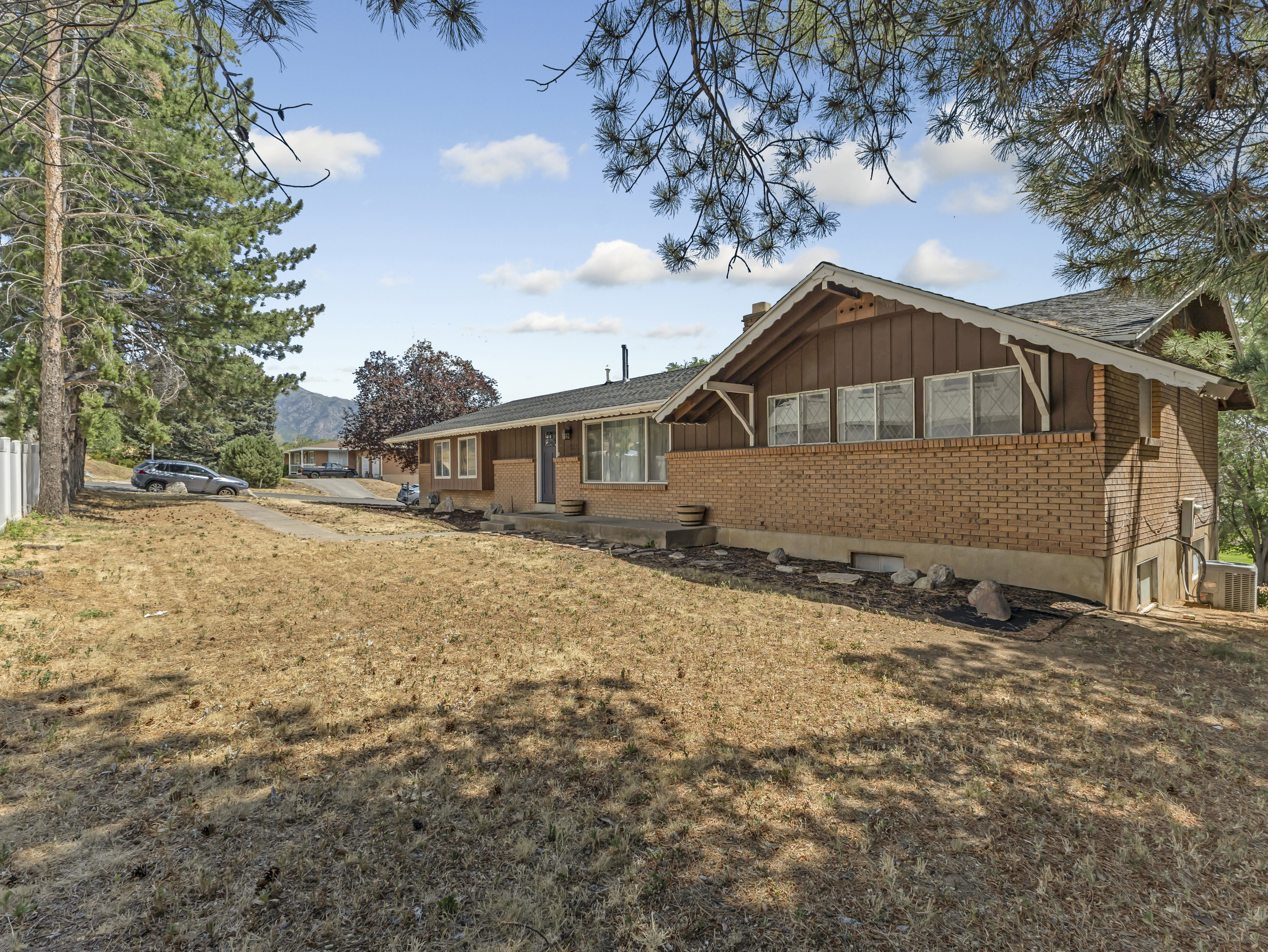 Ranch-style residence featuring a brick facade with brown siding, an asphalt shingle roof, and a prominent front entrance