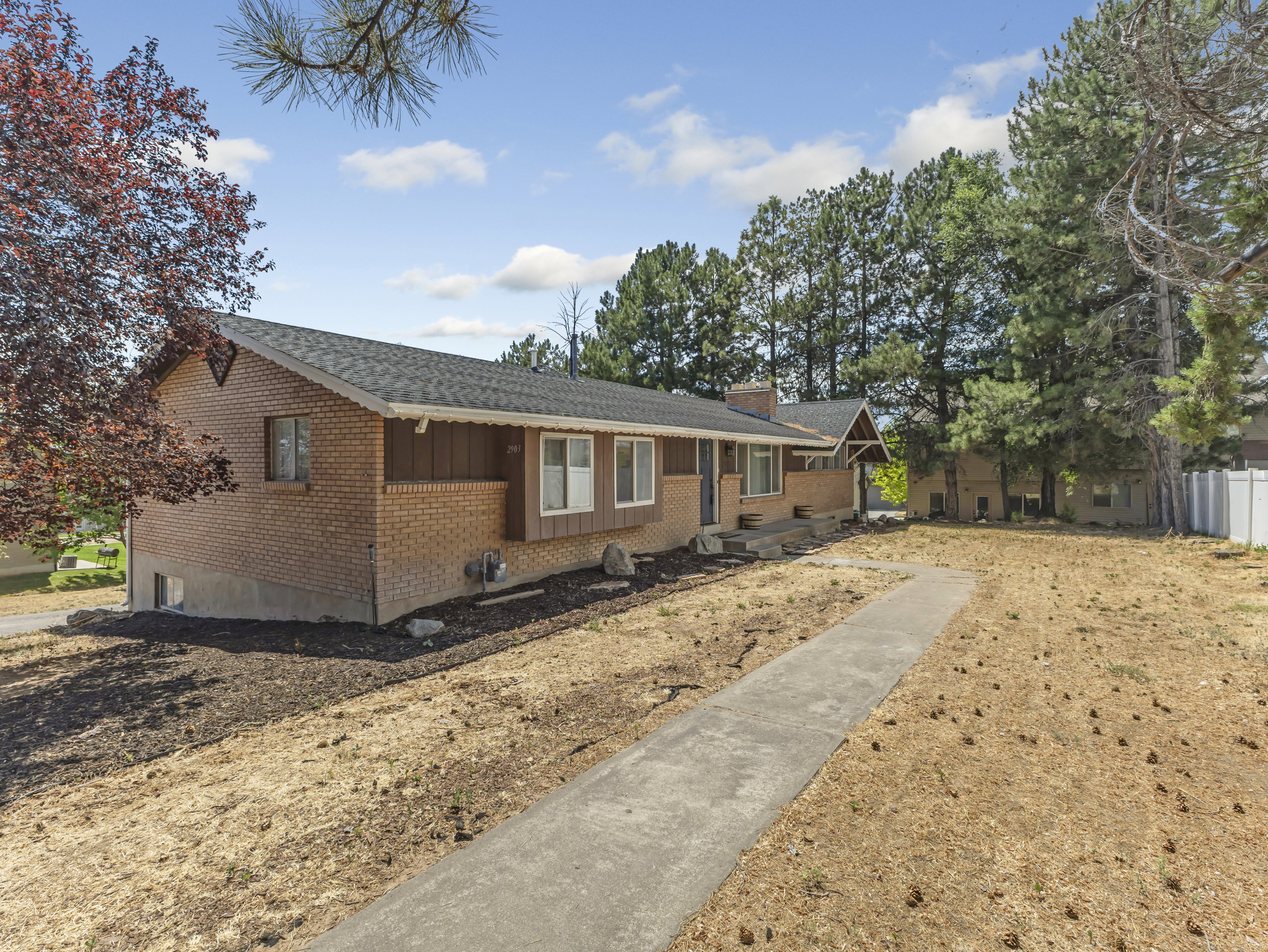 Brick and siding exterior featuring a covered entry and a long concrete walkway