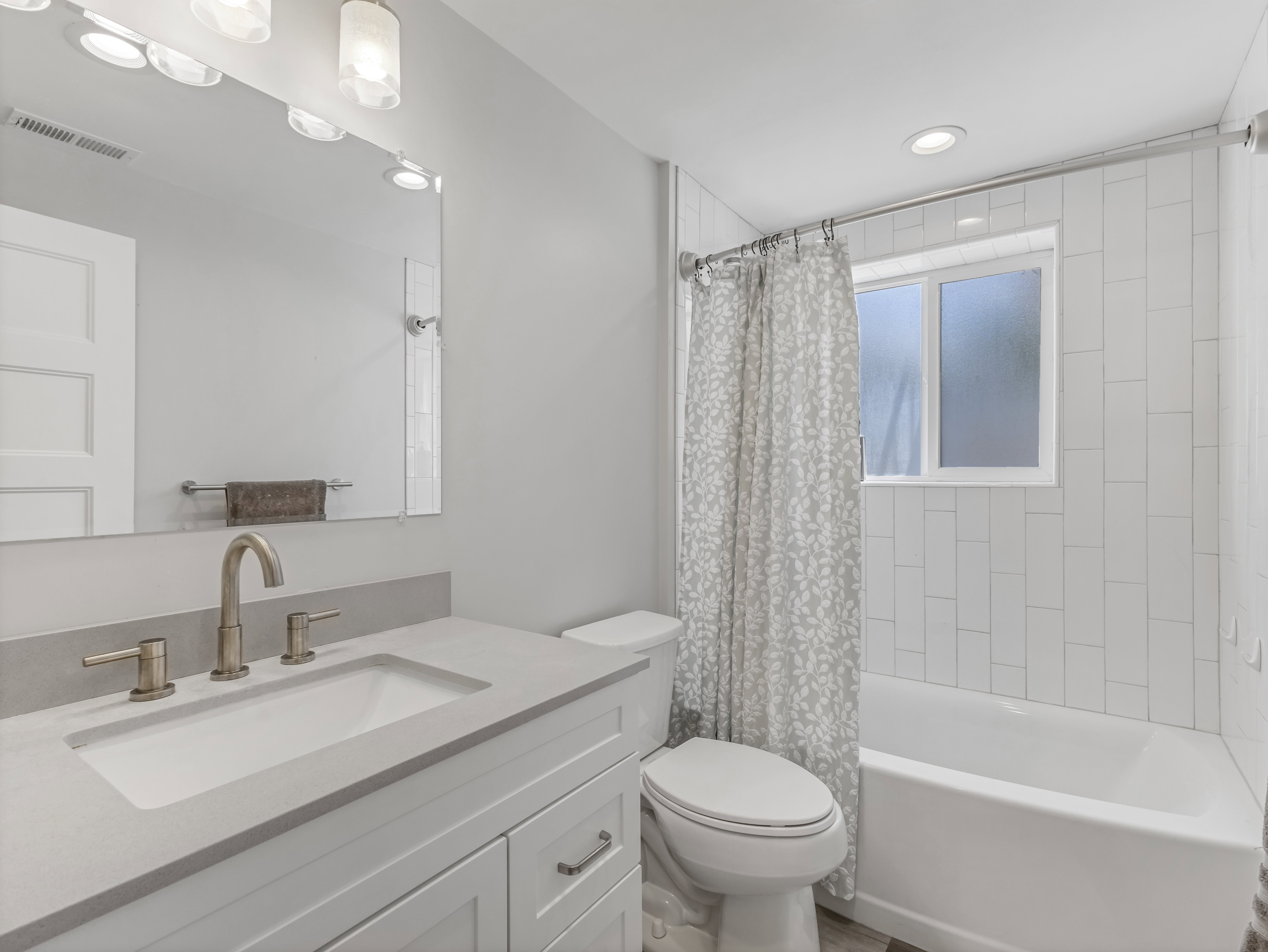 Bathroom featuring a white vanity with an integrated sink, brushed nickel faucet, and a large mirror