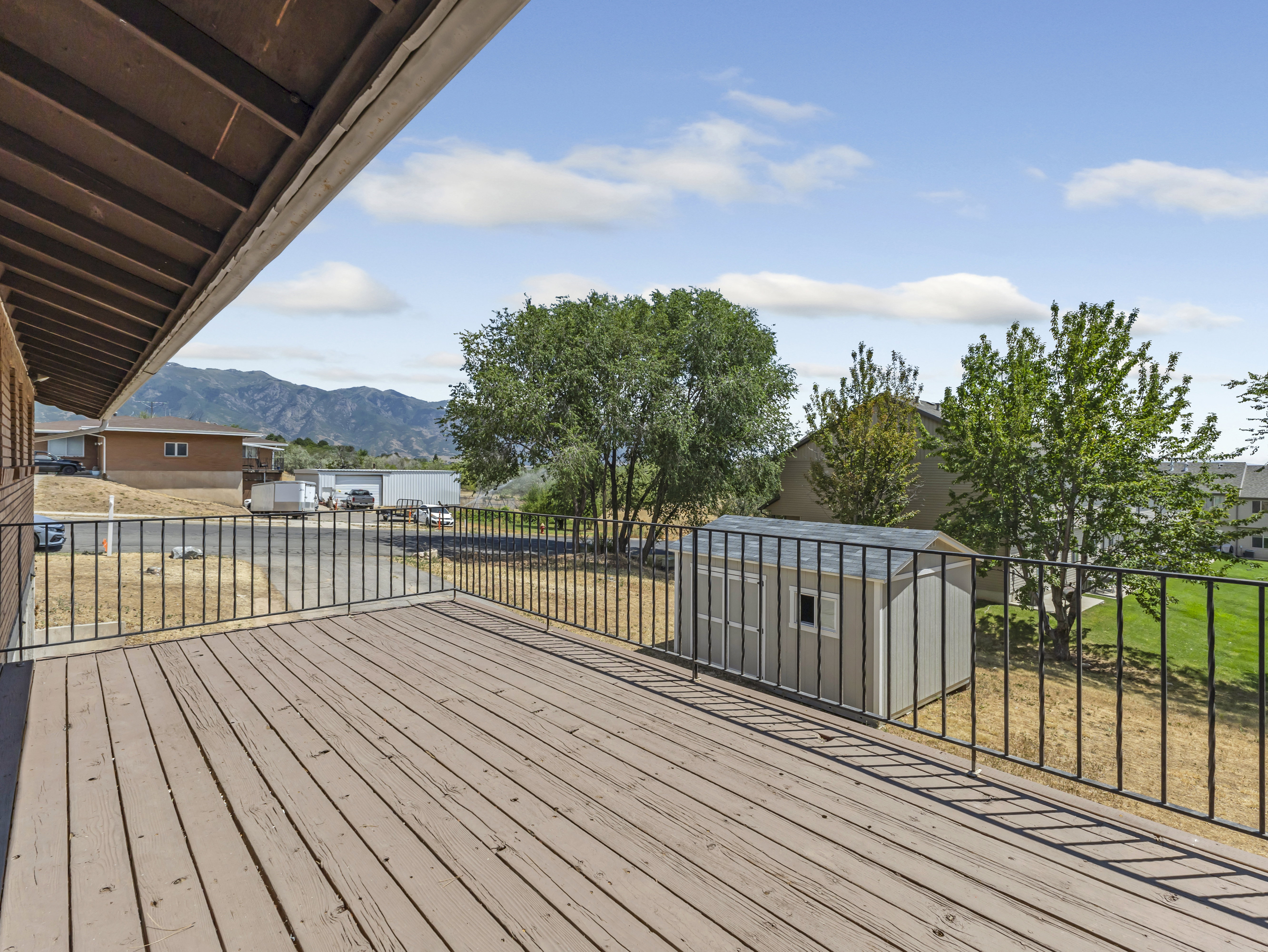 Expansive outdoor deck featuring wood-finish flooring and a black metal railing