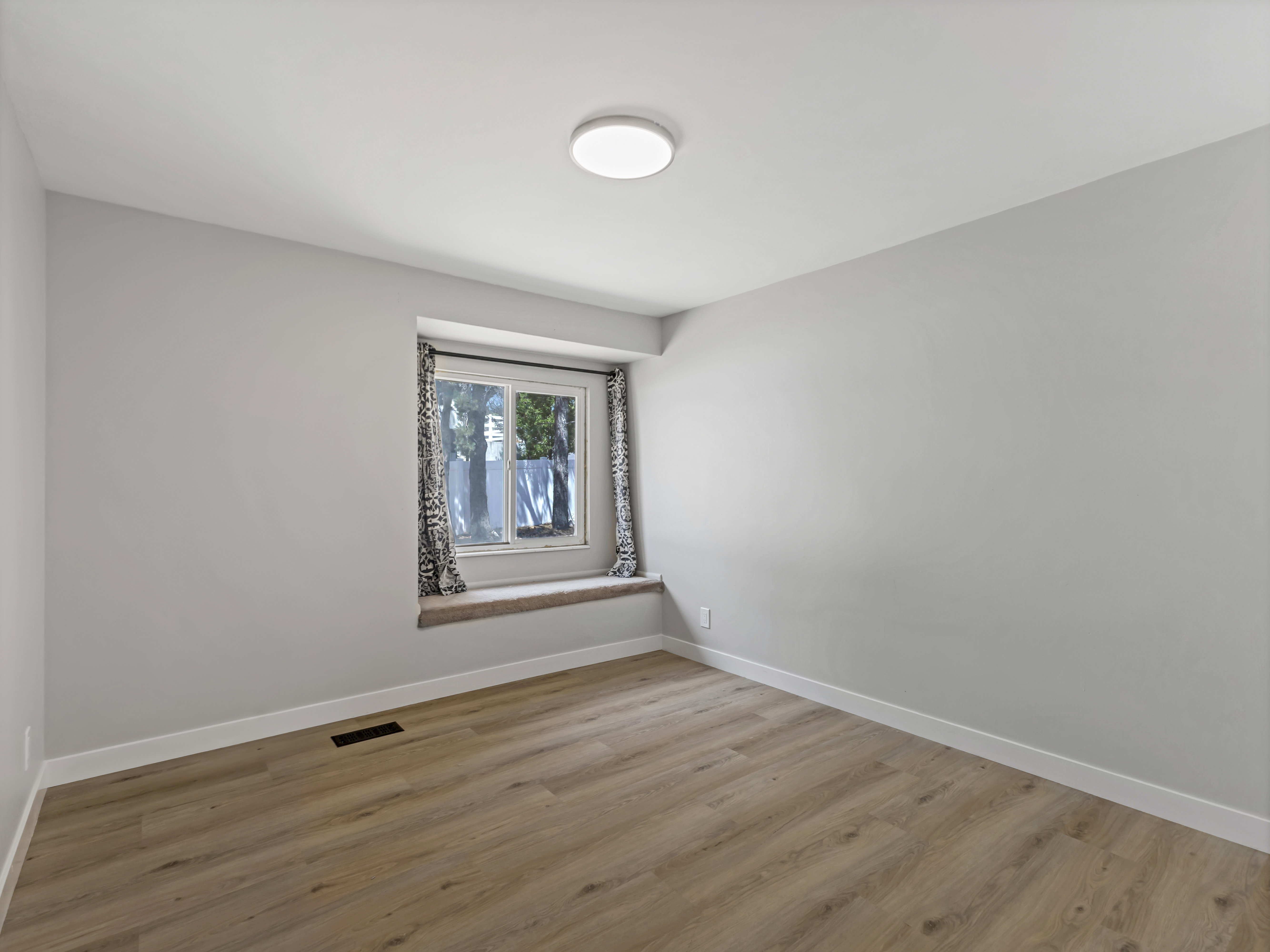 Neutral gray walls with white trim, wood-finish flooring, and a built-in window seat