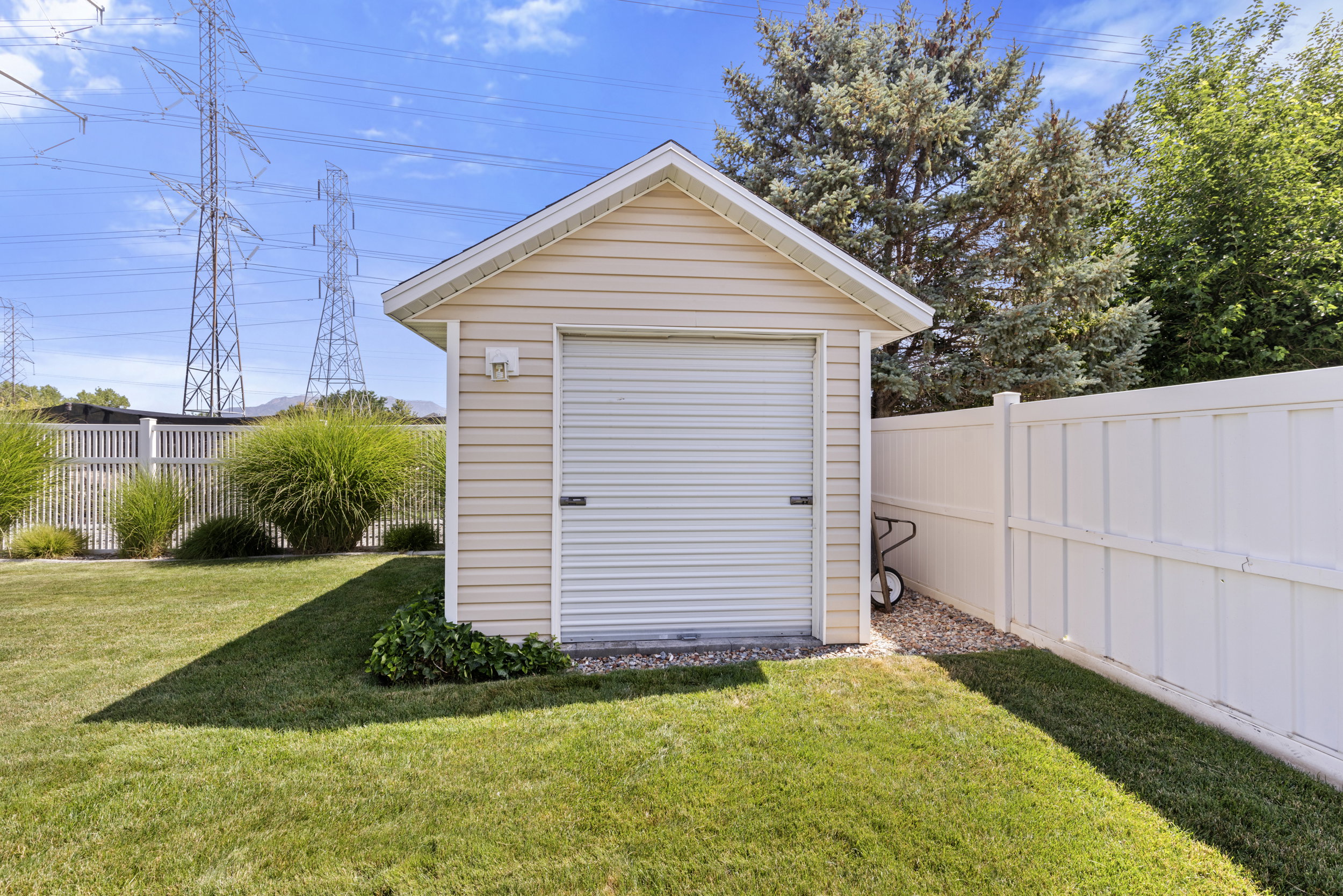 Detached shed with beige siding and a white roll-up door