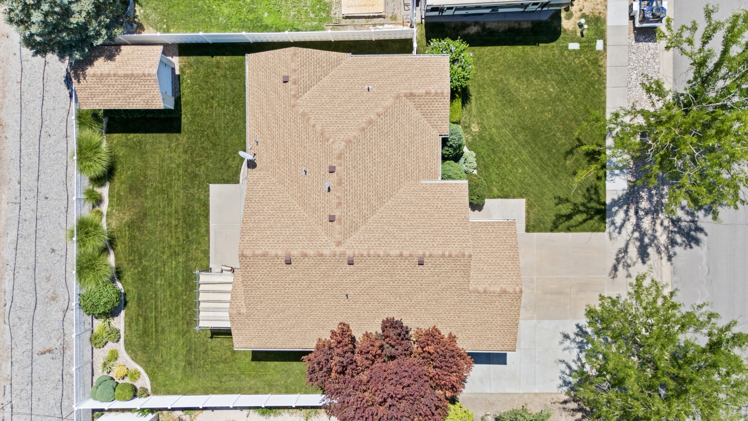 Expansive property featuring a multi-gabled shingle roof, concrete driveways, and a backyard patio