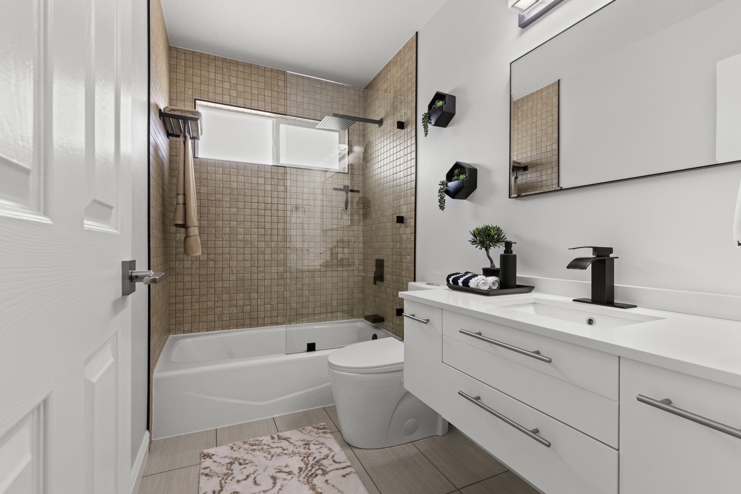Modern bathroom featuring a single floating vanity with a white countertop and integrated sink, matte black faucet, and a large framed mirror