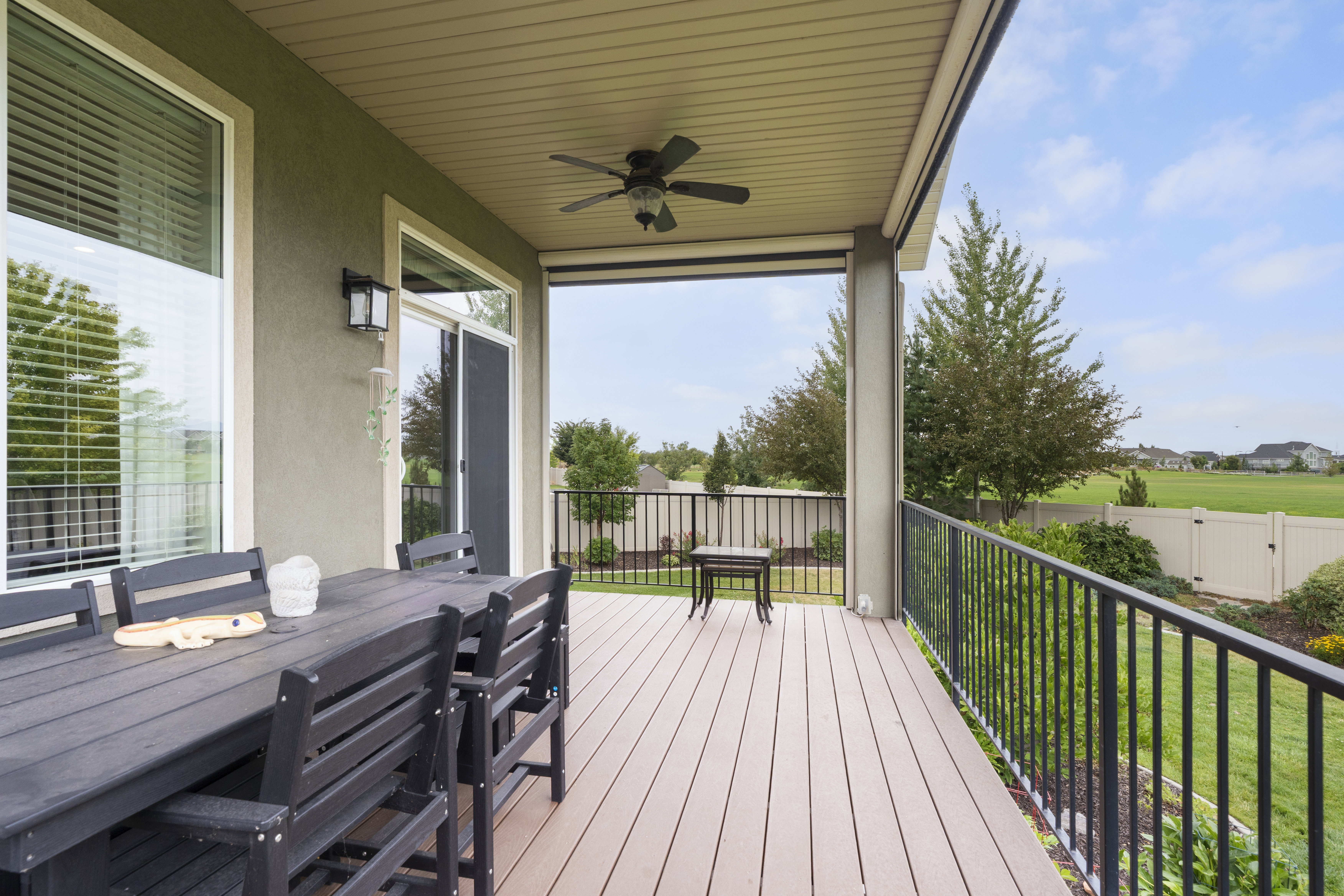 Covered composite deck featuring a ceiling fan, recessed lighting, stucco exterior, and black metal railings
