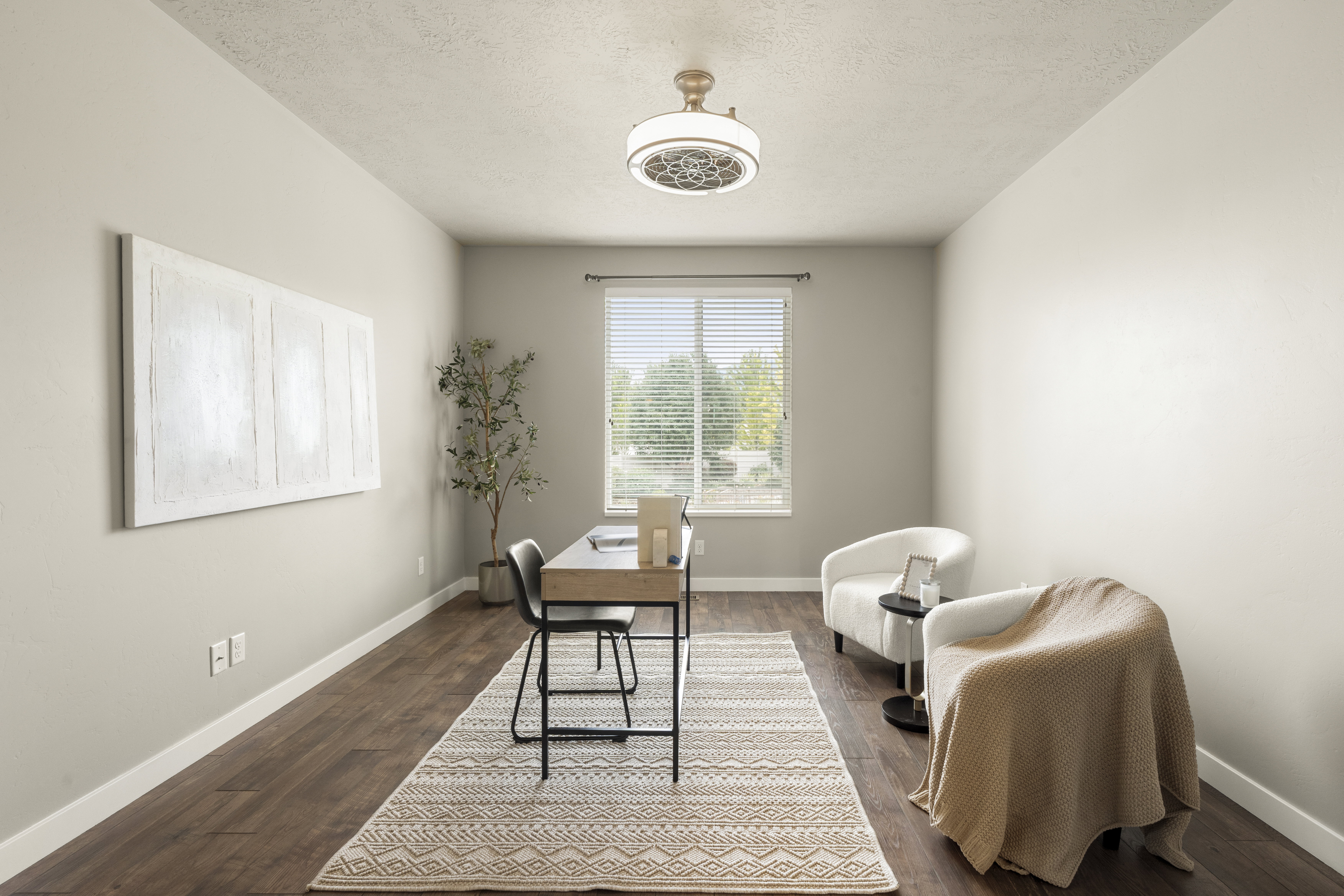 Spacious room featuring wood-finish flooring, neutral wall paint, and a ceiling-mounted light fixture with a decorative bronze finish