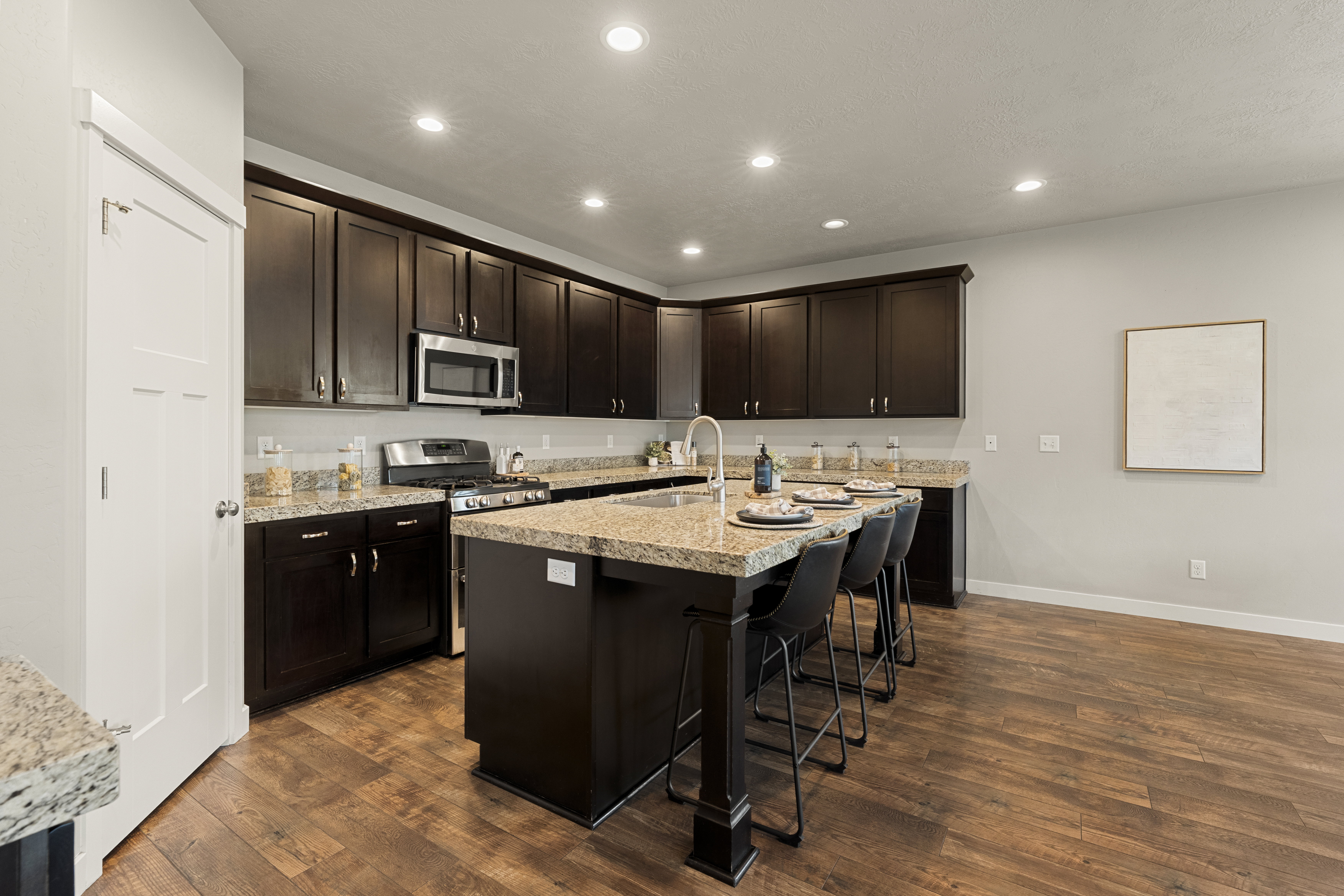 Kitchen featuring dark wood cabinetry, a central island with seating, stainless steel appliances, recessed lighting, and wood-finish flooring