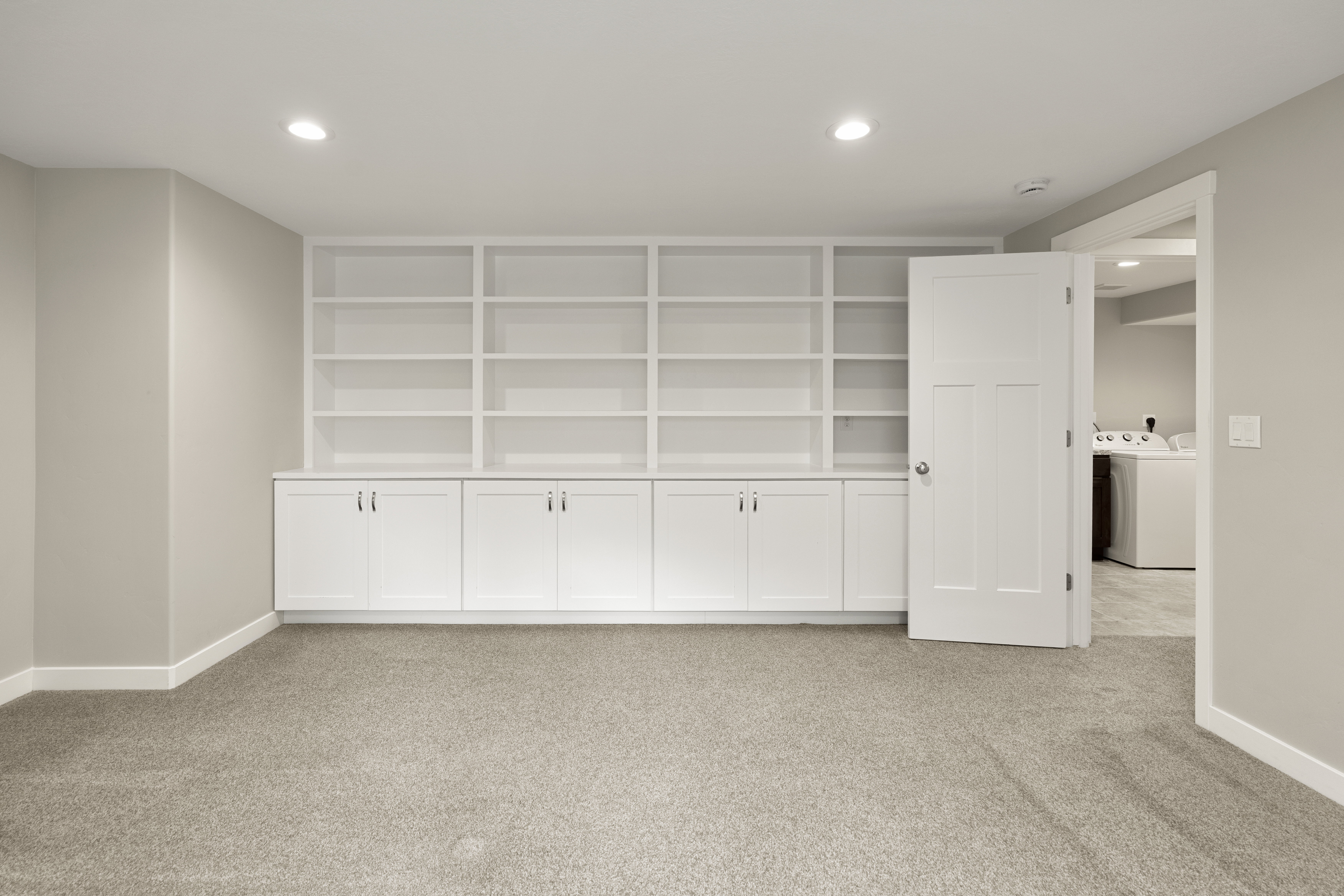 Built-in white cabinetry and shelving system with recessed lighting