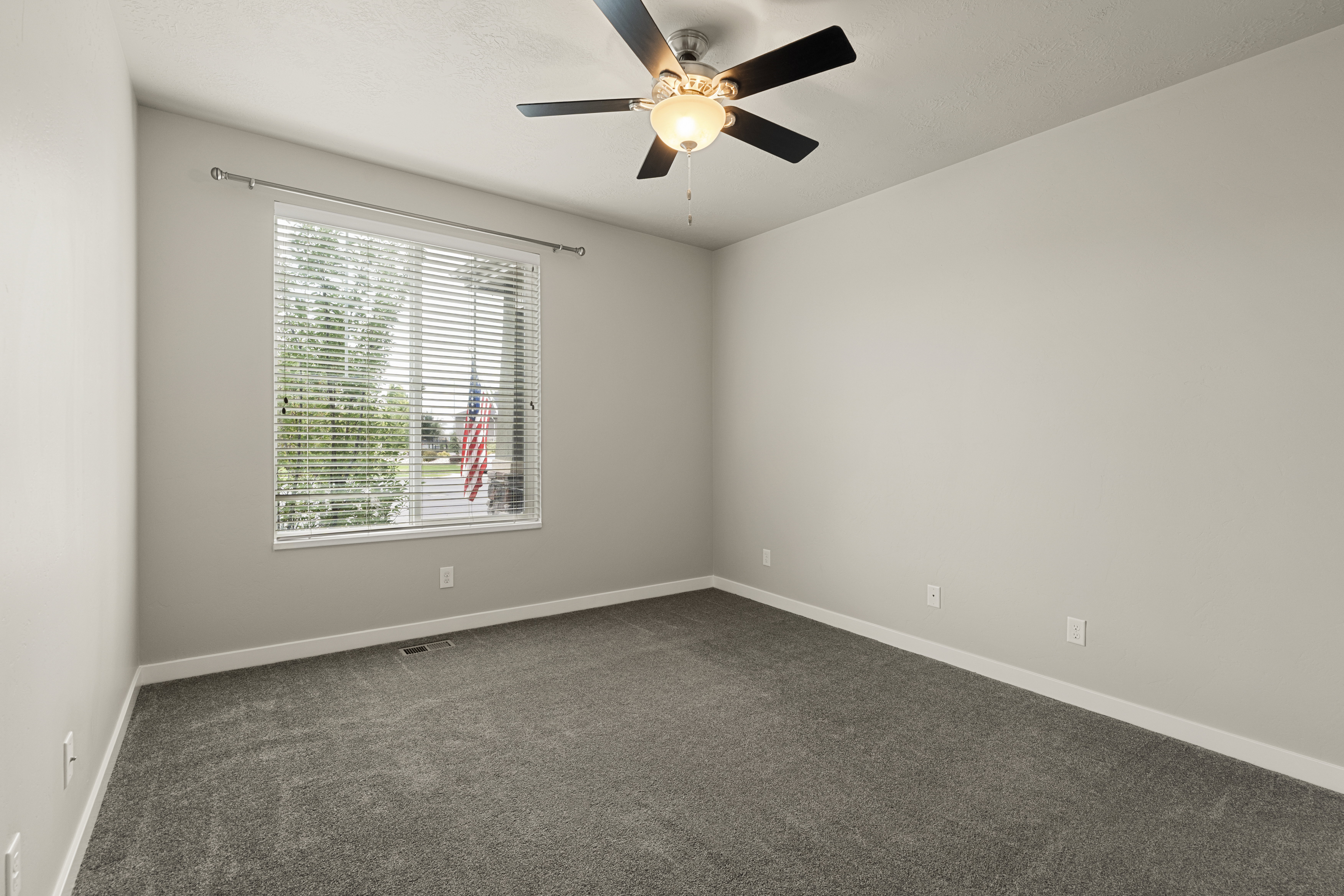 Bedroom featuring a large window with horizontal blinds, neutral wall paint, and gray carpet
