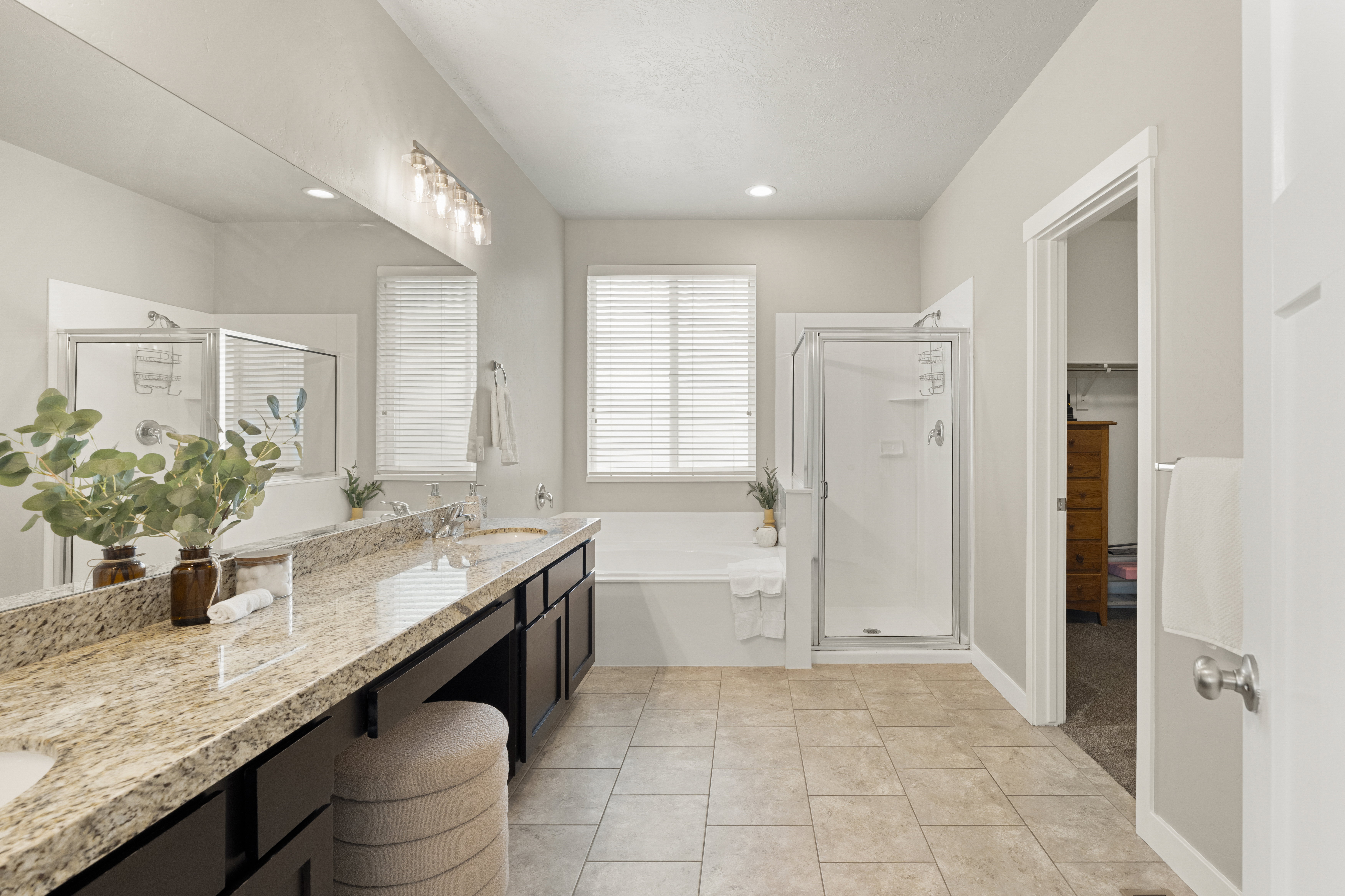 Spacious bathroom featuring a dual vanity with a granite-finish countertop, integrated sinks, and dark wood cabinetry