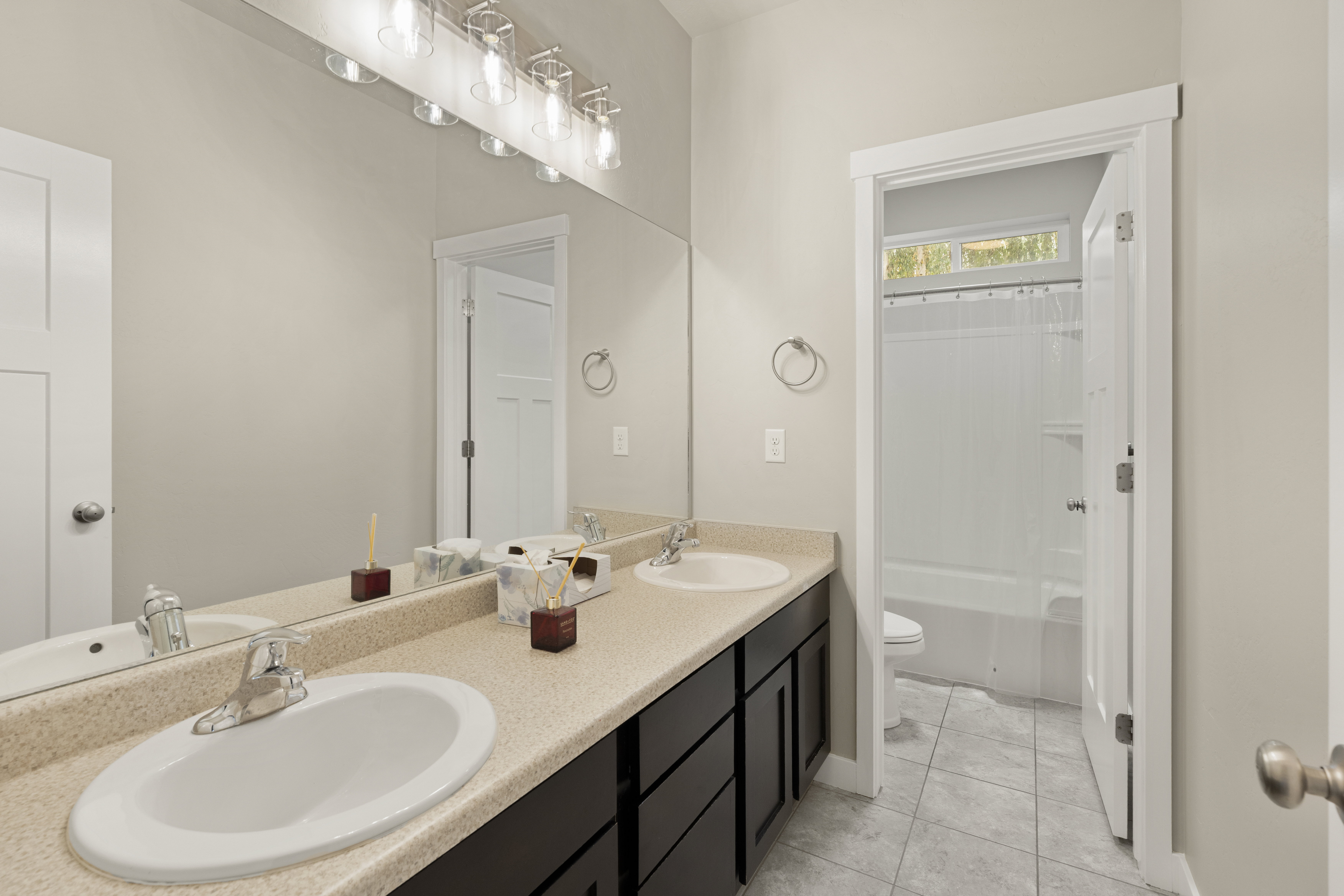Bathroom featuring a dual vanity with dark wood cabinetry, solid surface countertop, and chrome fixtures