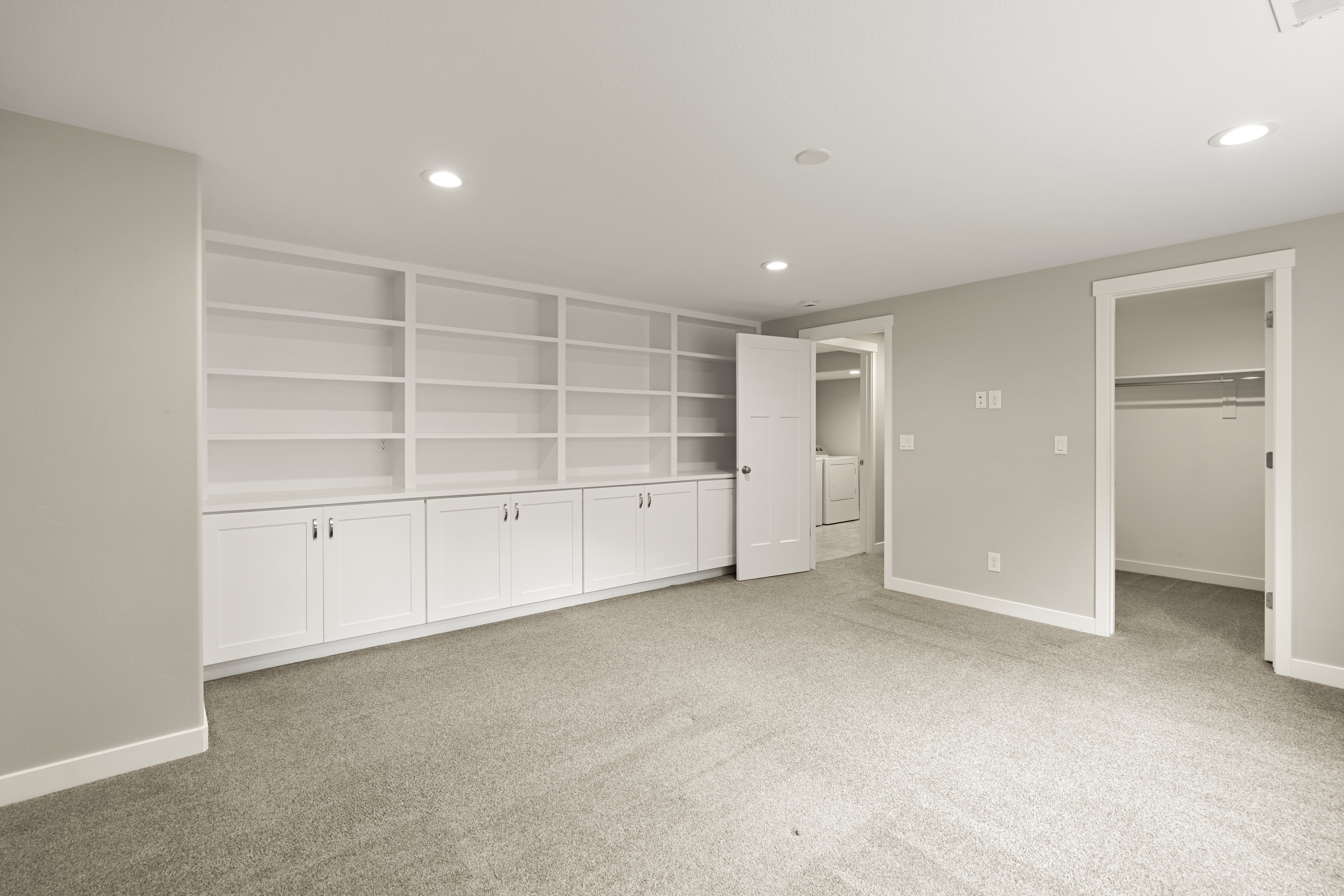 Spacious room featuring extensive built-in white cabinetry and shelving