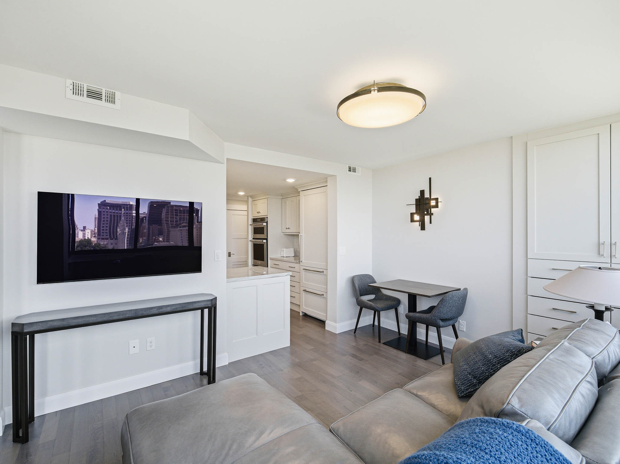 Open-concept living area with wood-finish flooring, recessed lighting, and a modern ceiling fixture