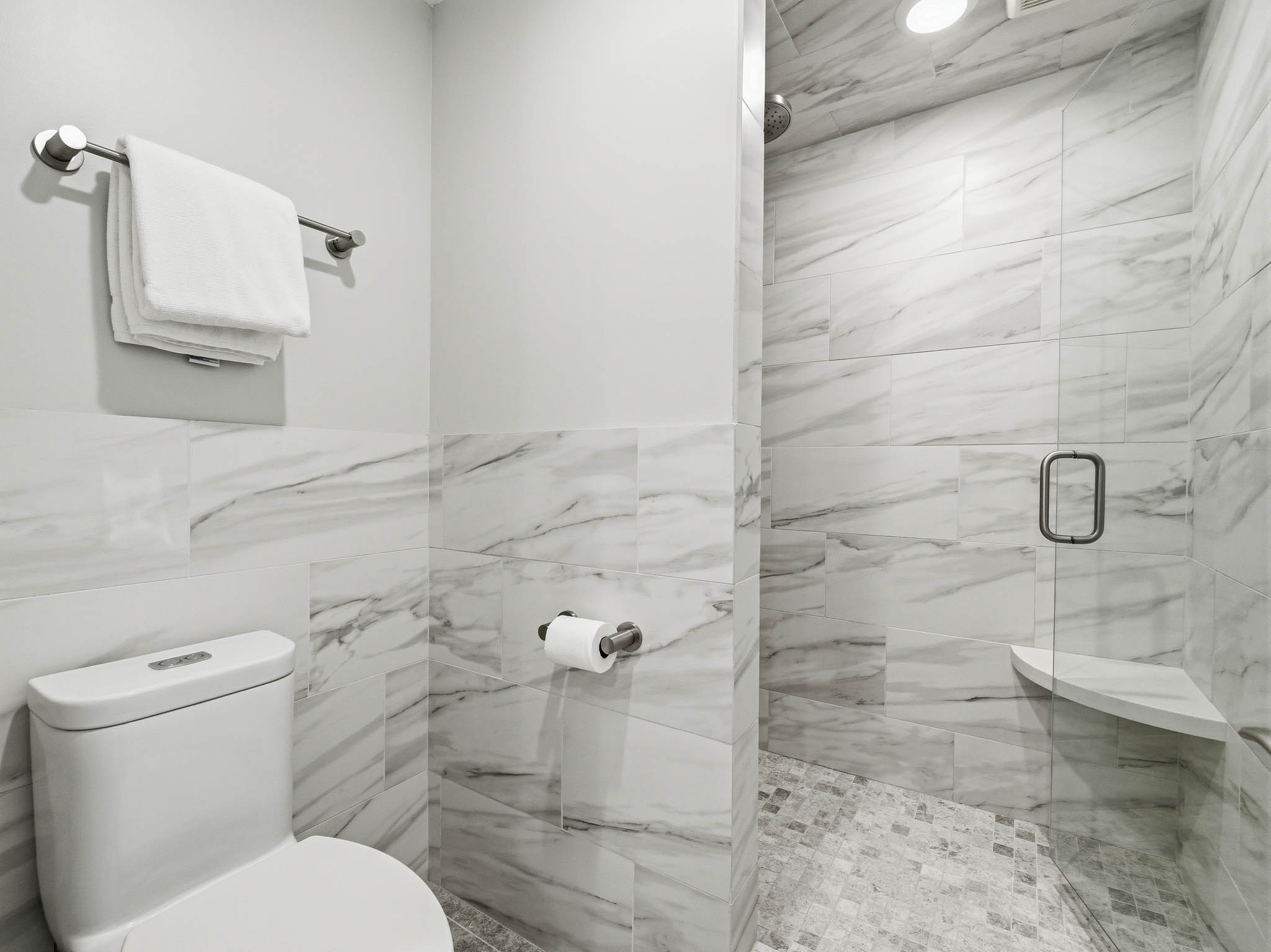 Walk-in shower with clear glass enclosure and corner shelf