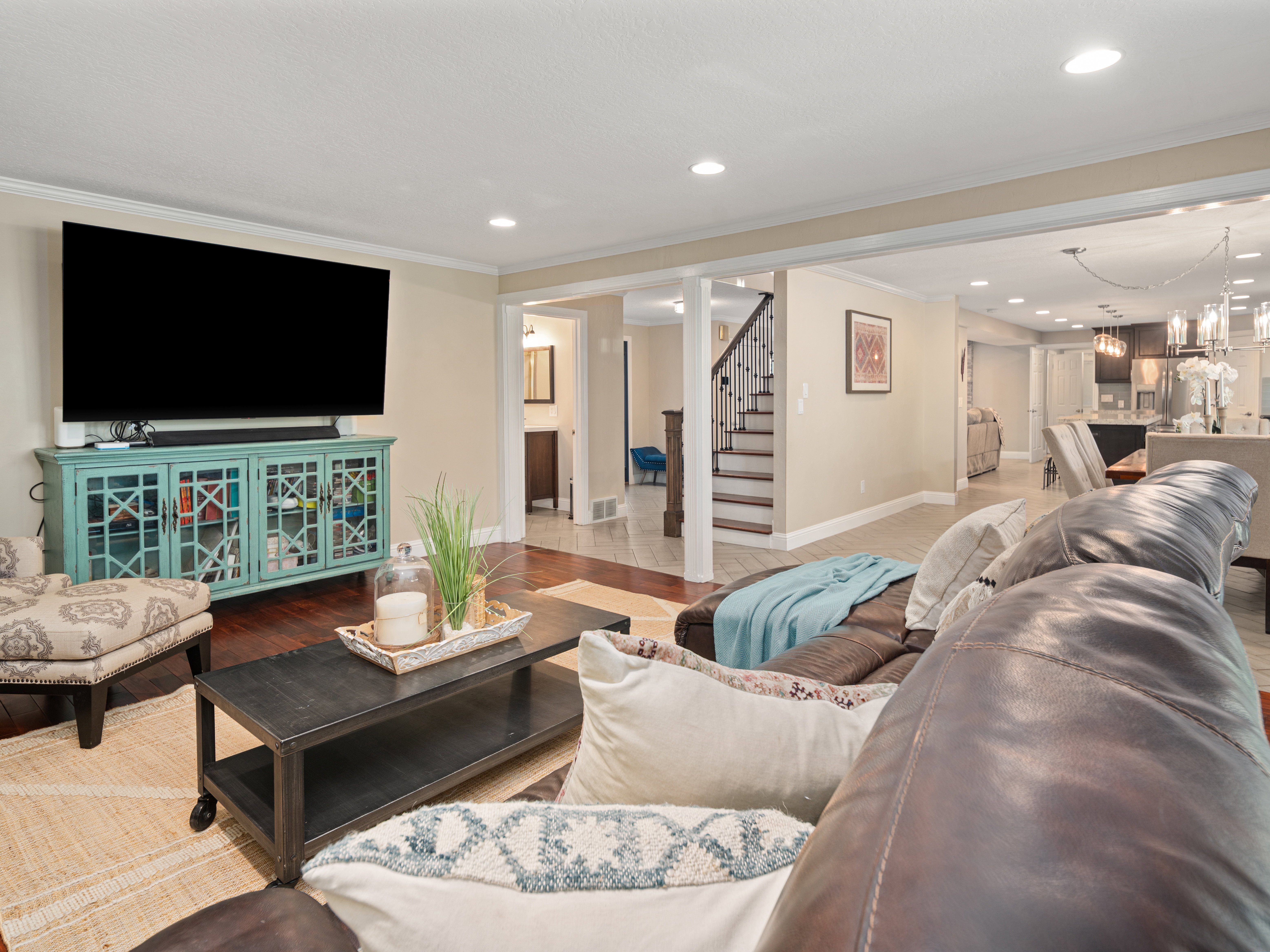 Living area featuring wood-finish flooring, crown molding, recessed lighting, and a broad framed opening