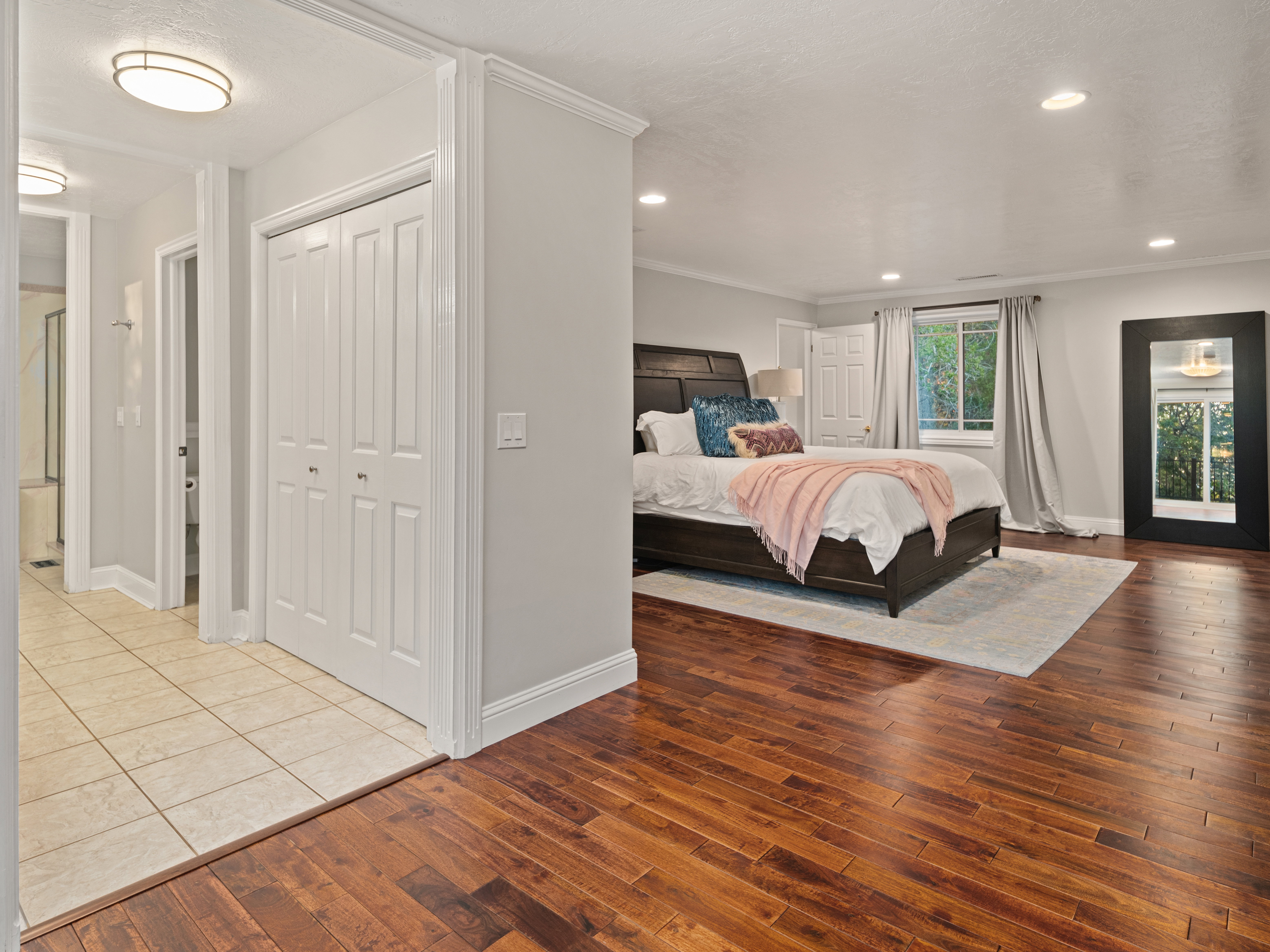Spacious room featuring rich wood-finish flooring, recessed lighting, and a large window with outdoor scenery