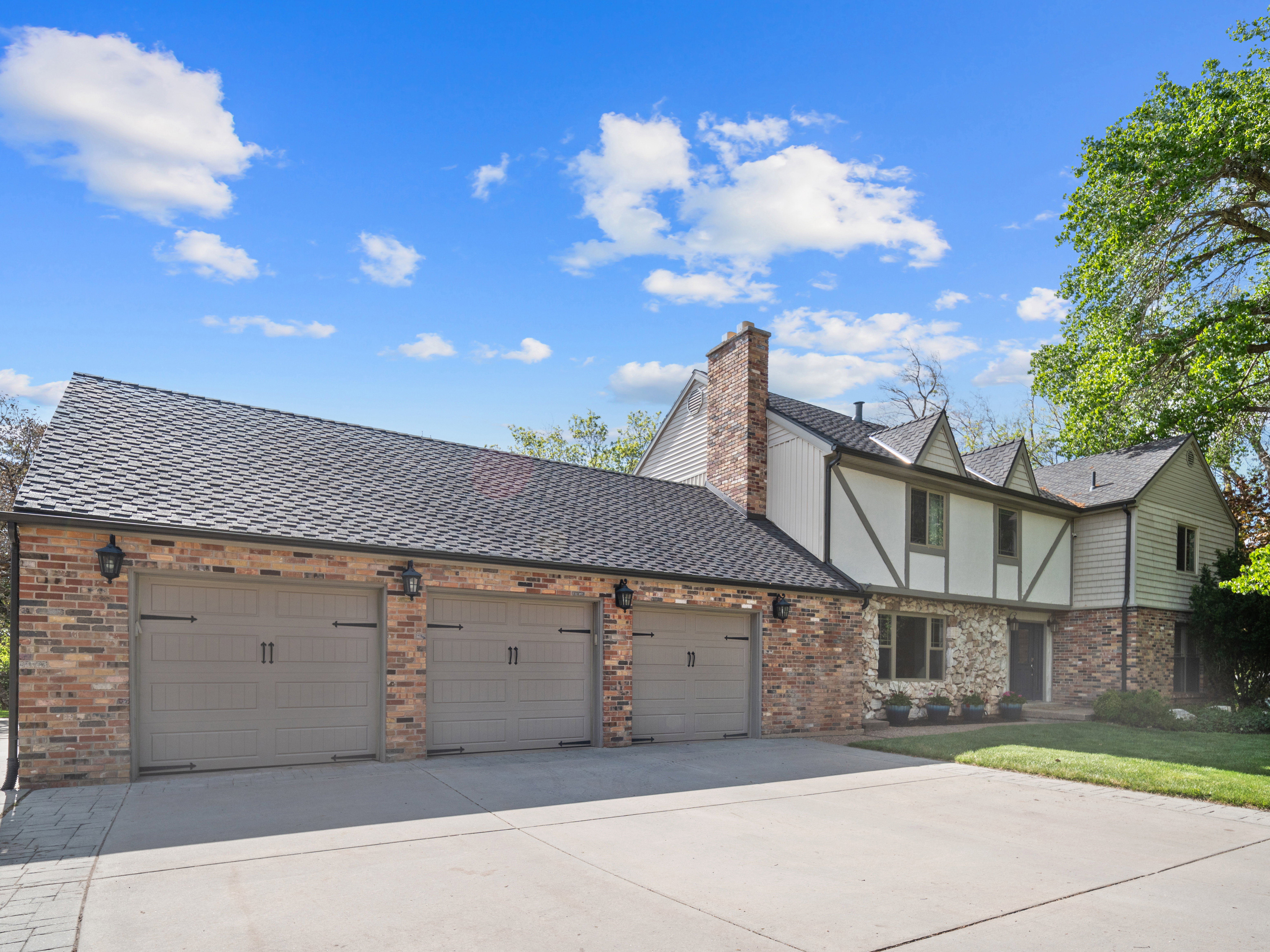Brick and siding exterior featuring a three-car garage with carriage-style doors