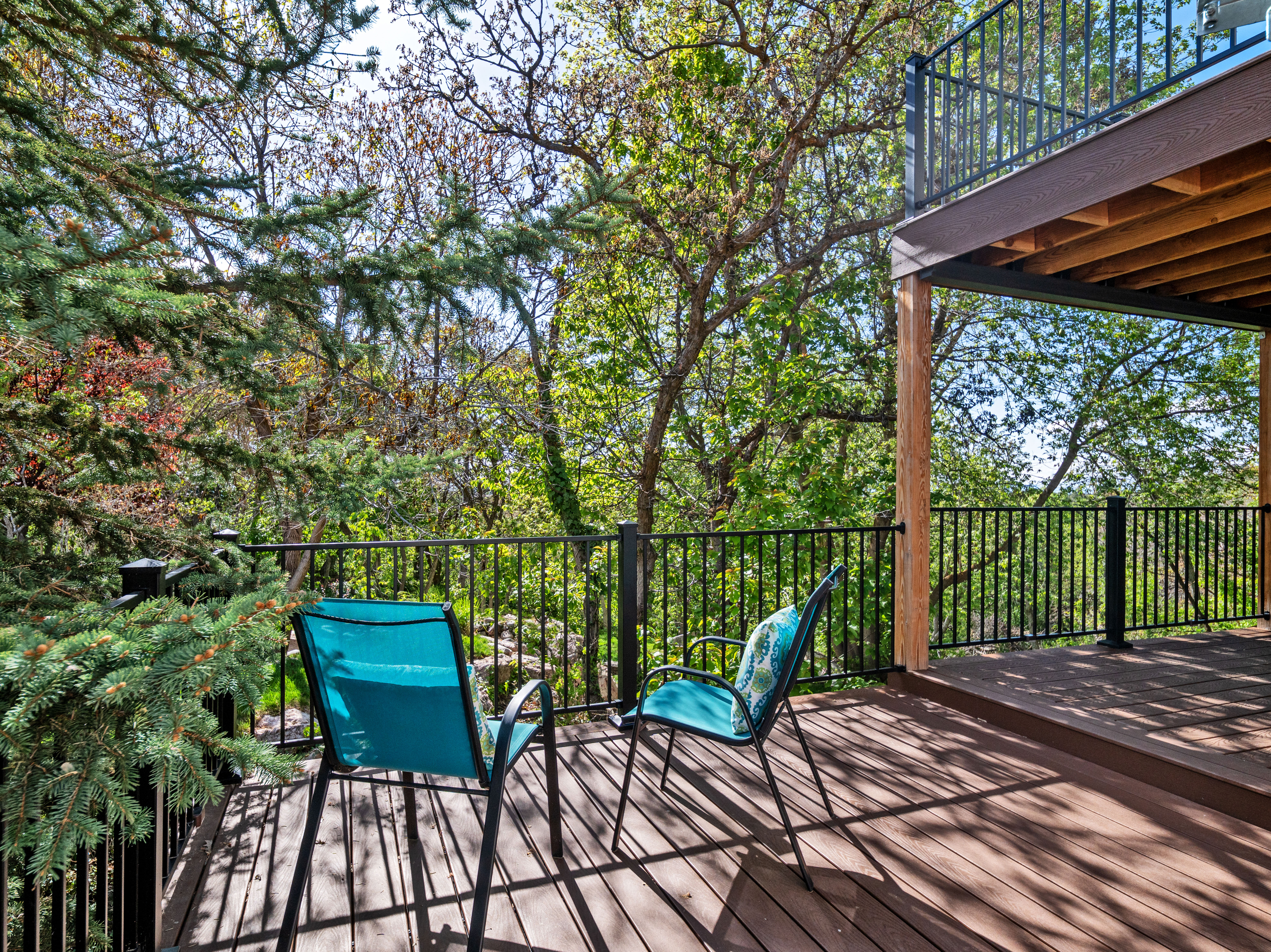 Multi-level outdoor deck featuring wood-finish flooring, black metal railings, and natural surroundings