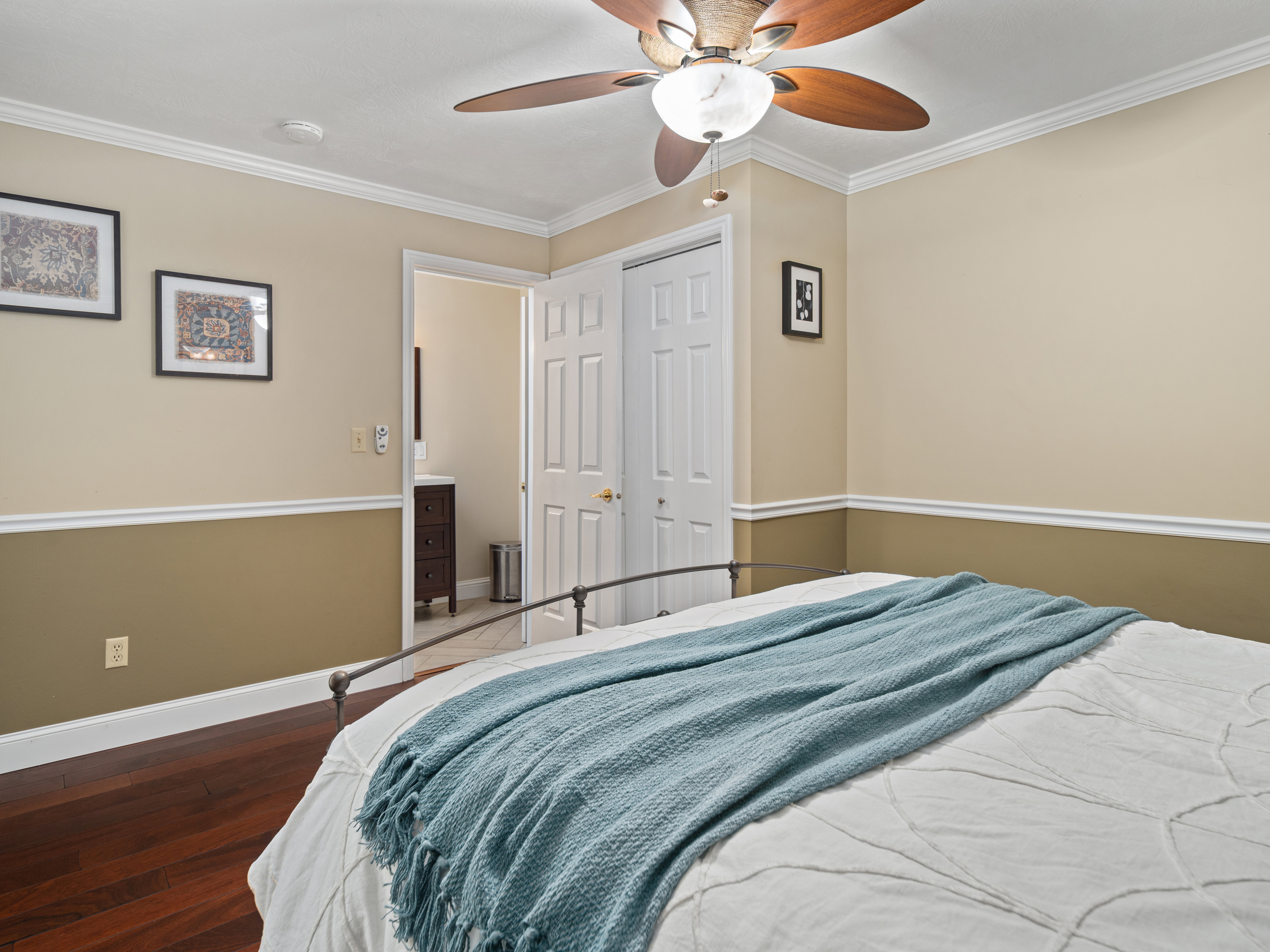 Room featuring a ceiling fan with integrated lighting, crown molding, two-tone wall paint, and wood-finish flooring
