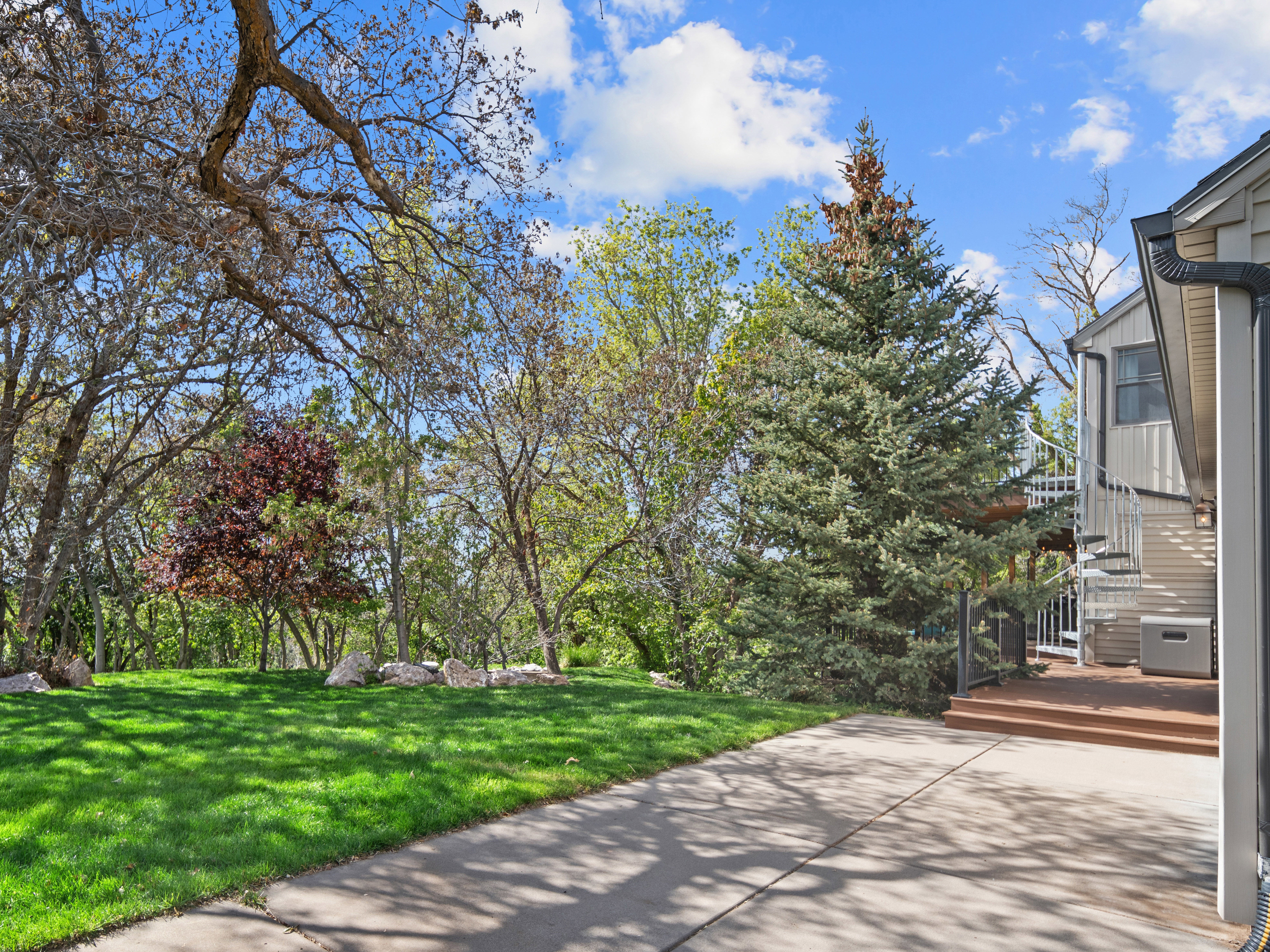 Expansive lawn area bordered by mature trees and natural rock landscaping