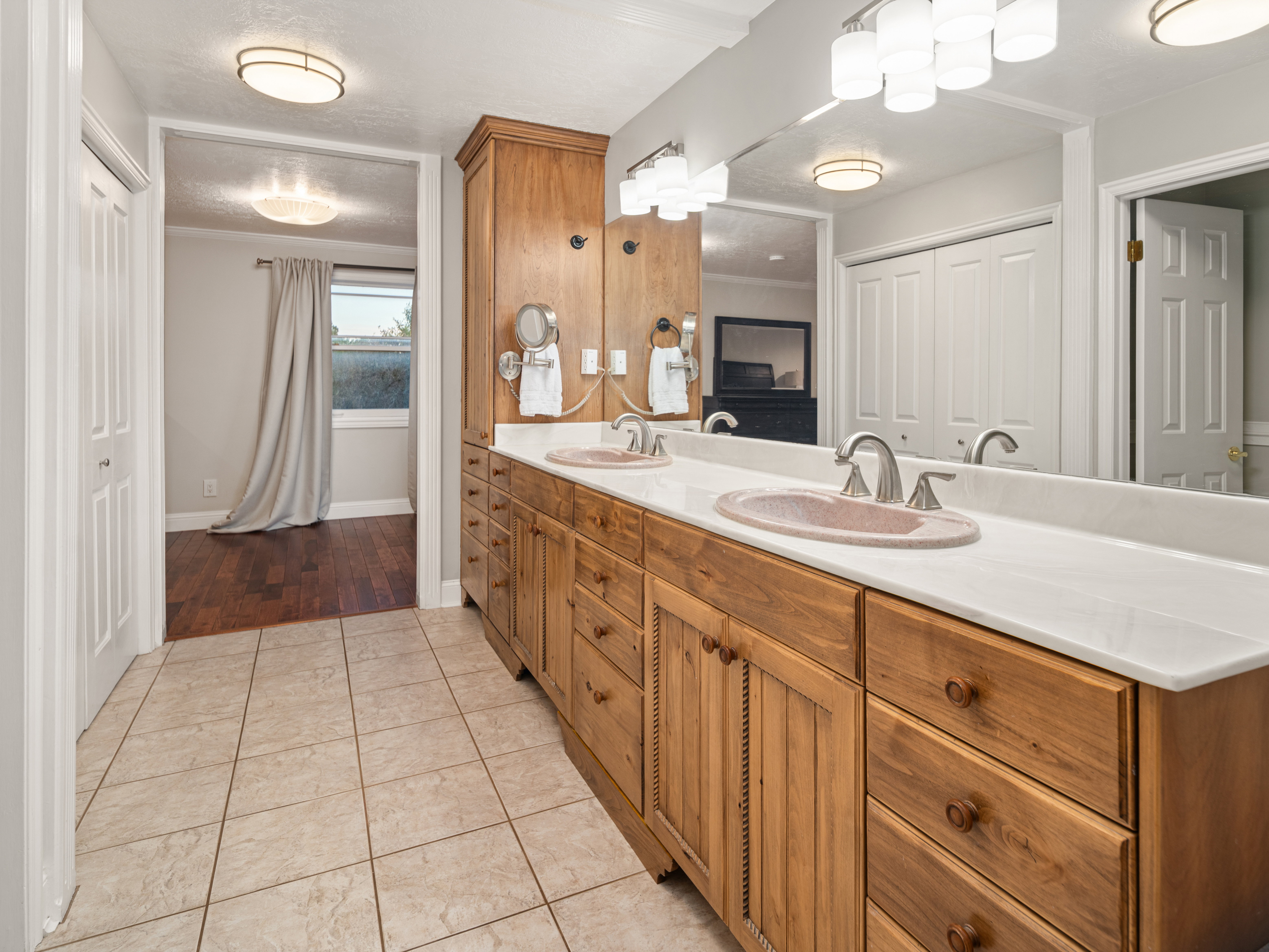 Dual vanity with wood cabinetry, integrated sinks, and polished chrome fixtures