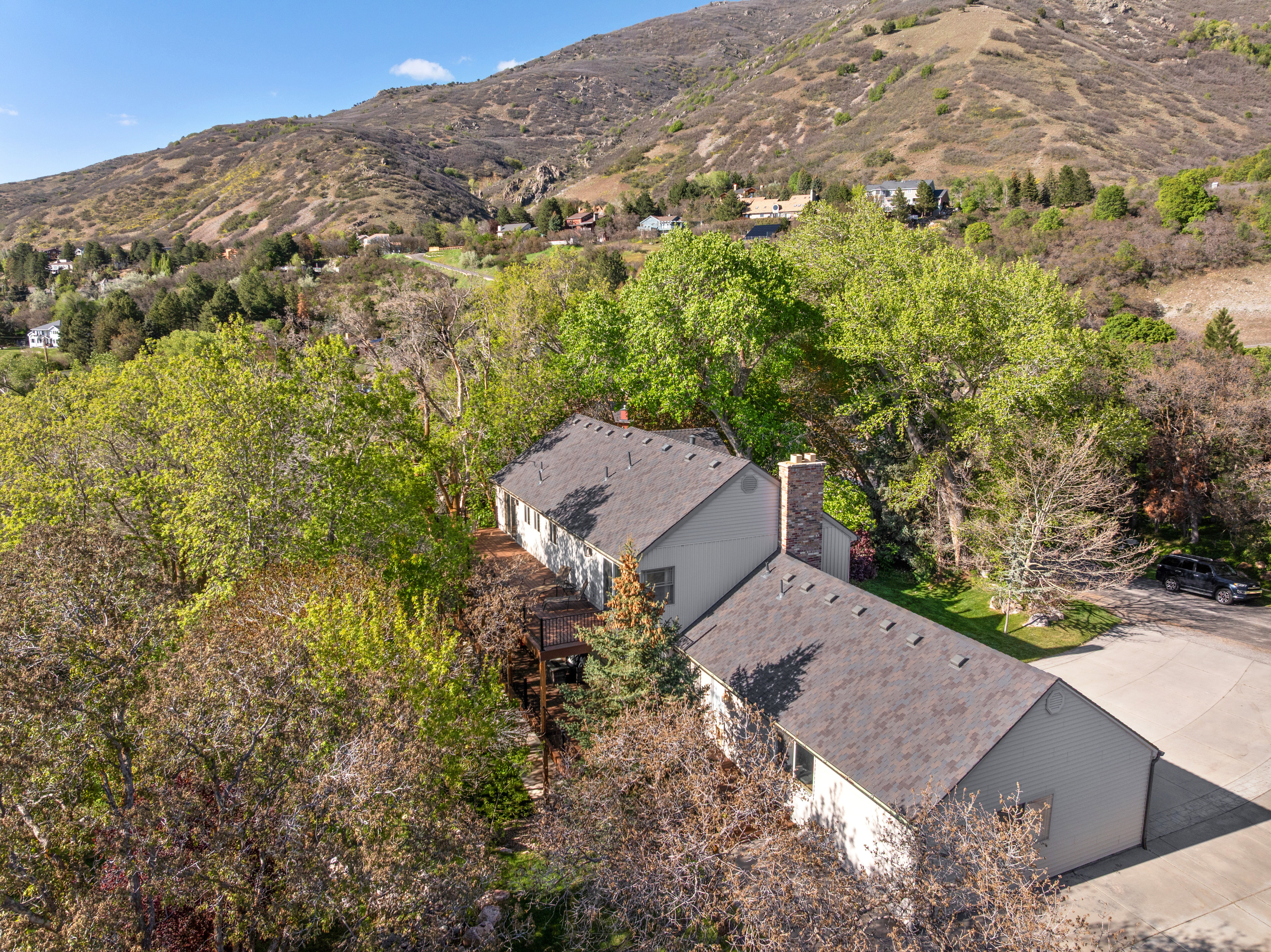 Property featuring a neutral-toned exterior, dark shingle roofing, and a prominent stone chimney