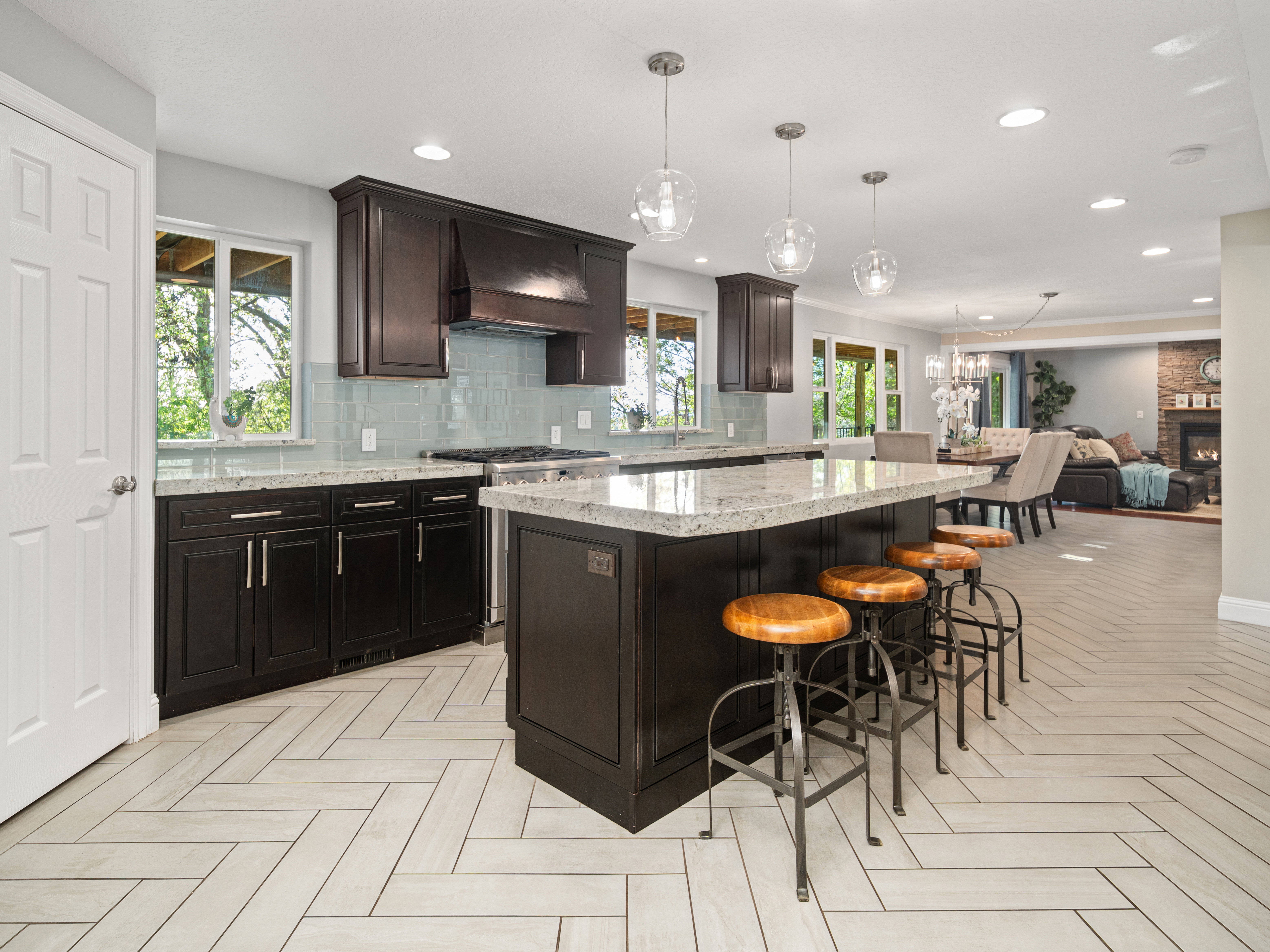 Gourmet kitchen featuring a large island with seating, dark wood cabinetry, light quartz countertops, and a subway tile backsplash