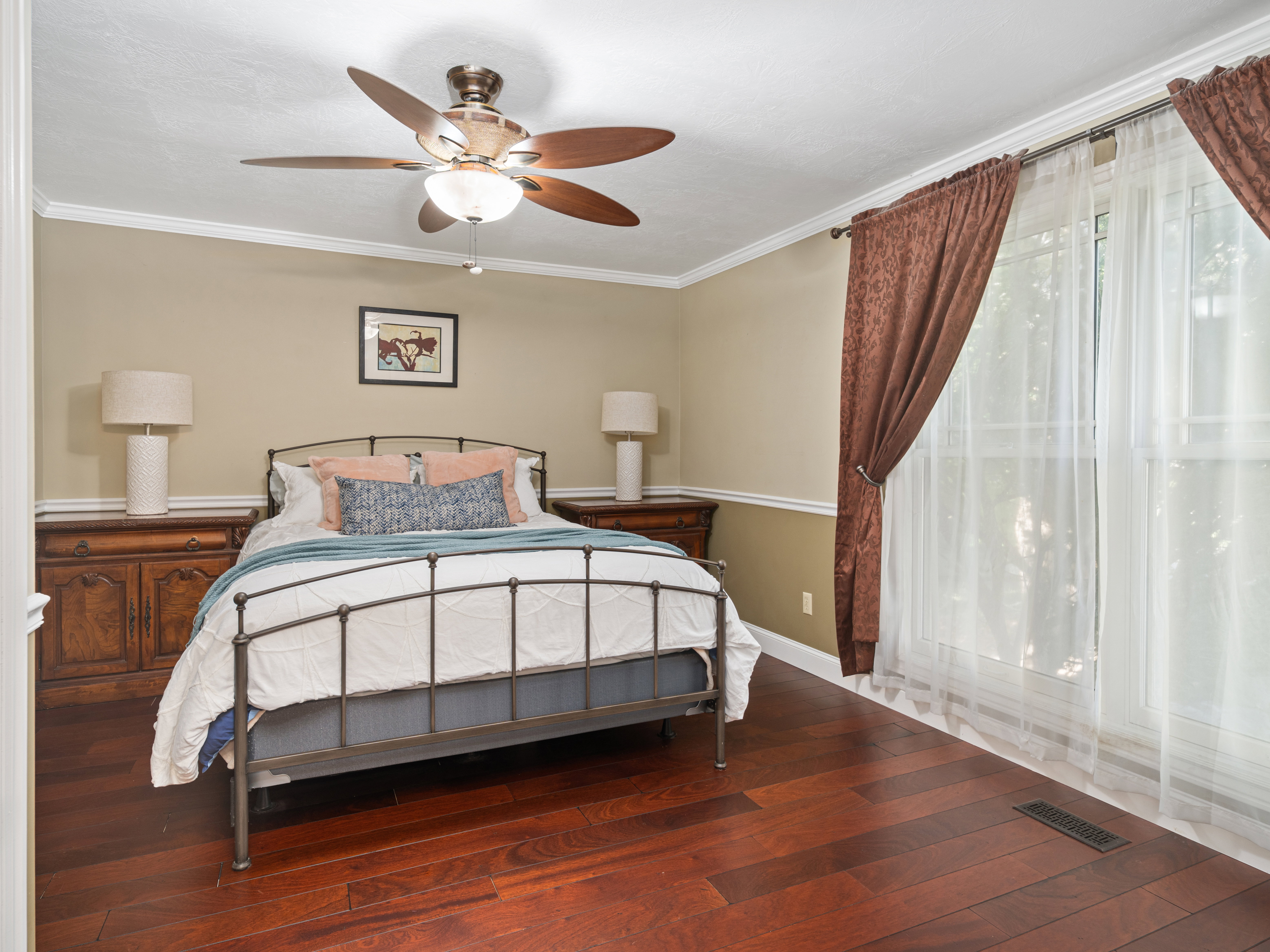 Warm wood-finish flooring complements the neutral wall color and white crown molding